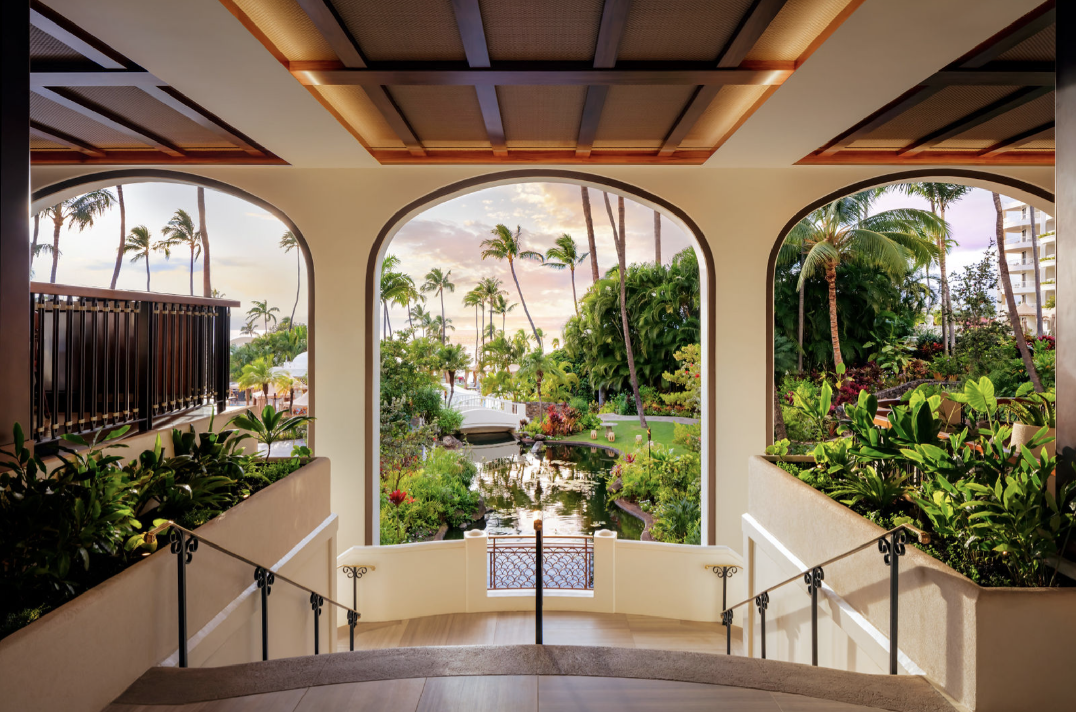 Open-air arches leading to lush tropical gardens, koi pond, and ocean access at Fairmont Kea Lani lobby in Maui