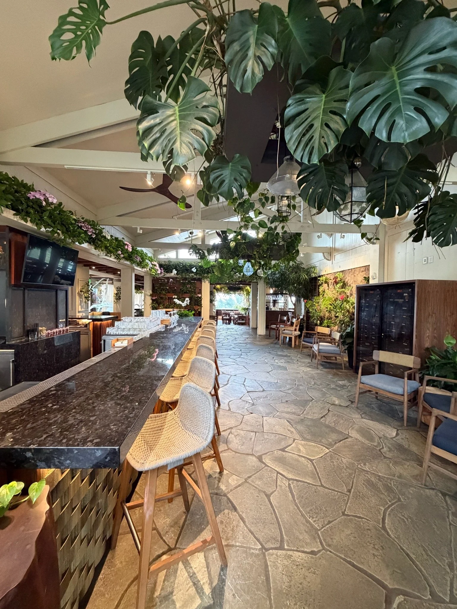 Banyan Tree restaurant at The Ritz-Carlton Kapalua featuring an open-air bar, lush greenery, and tropical indoor-outdoor dining in Maui, Hawaii