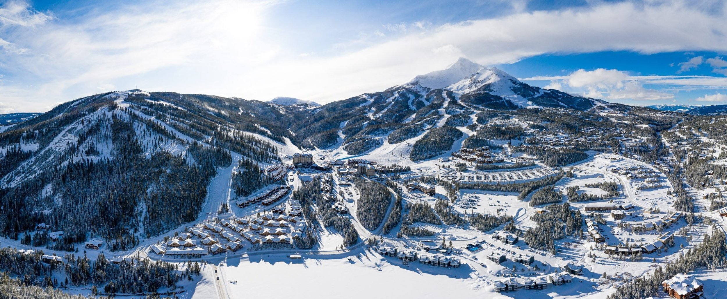 Aerial view of Big Sky Resort in Montana covered in snow with ski runs, mountain village, and alpine landscape