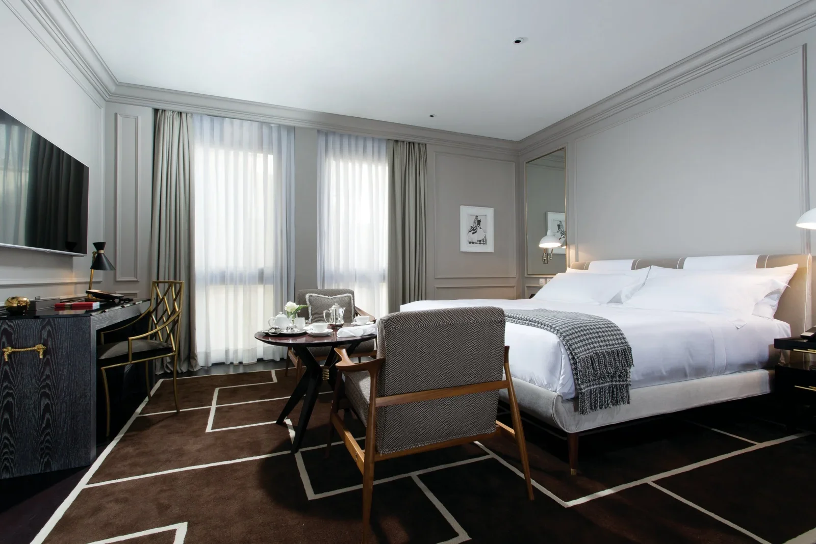 Elegant luxury hotel room in Florence, Italy, featuring neutral interiors, a king bed, contemporary furnishings, and floor-to-ceiling windows.