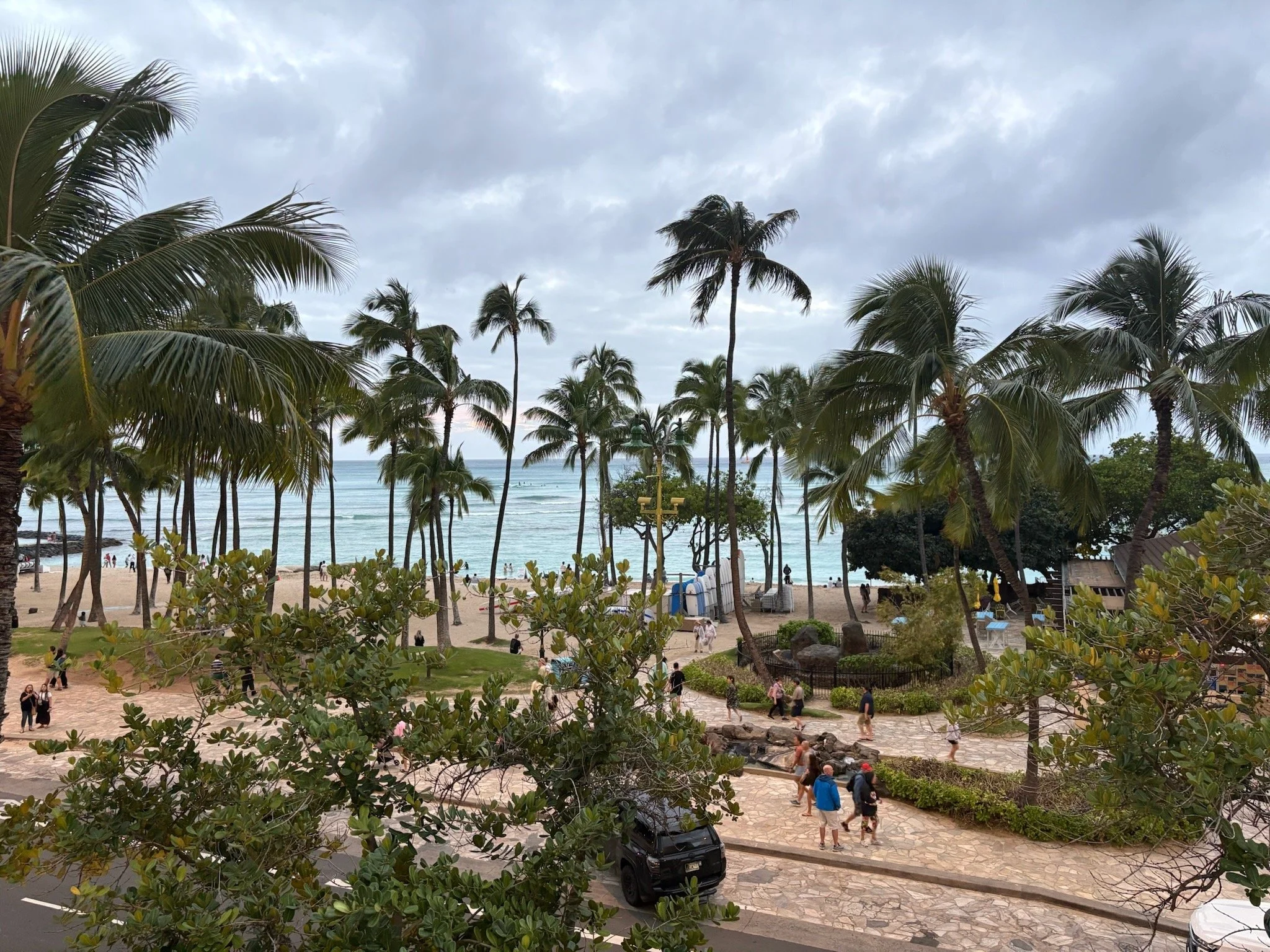 View of Waikiki Beach and the Pacific Ocean from Hyatt Regency Waikiki Beach Resort & Spa with palm trees, beachfront promenade, and Diamond Head area shoreline in Honolulu, Oahu.