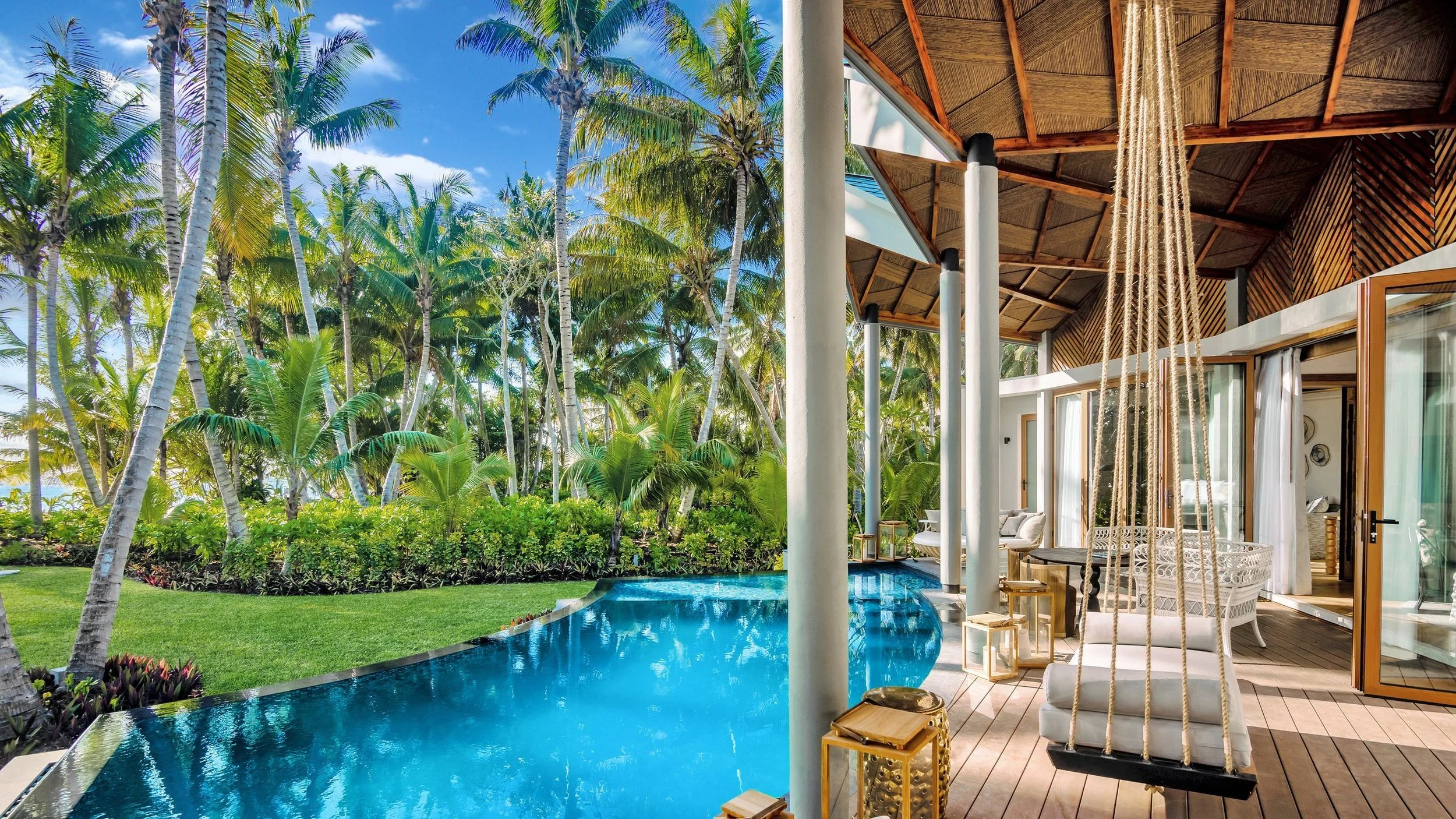 Private villa at the Waldorf Astoria Seychelles Platte Island featuring a lagoon-style pool, swing seating, and lush palm trees—ideal for a luxury honeymoon or tropical escape.