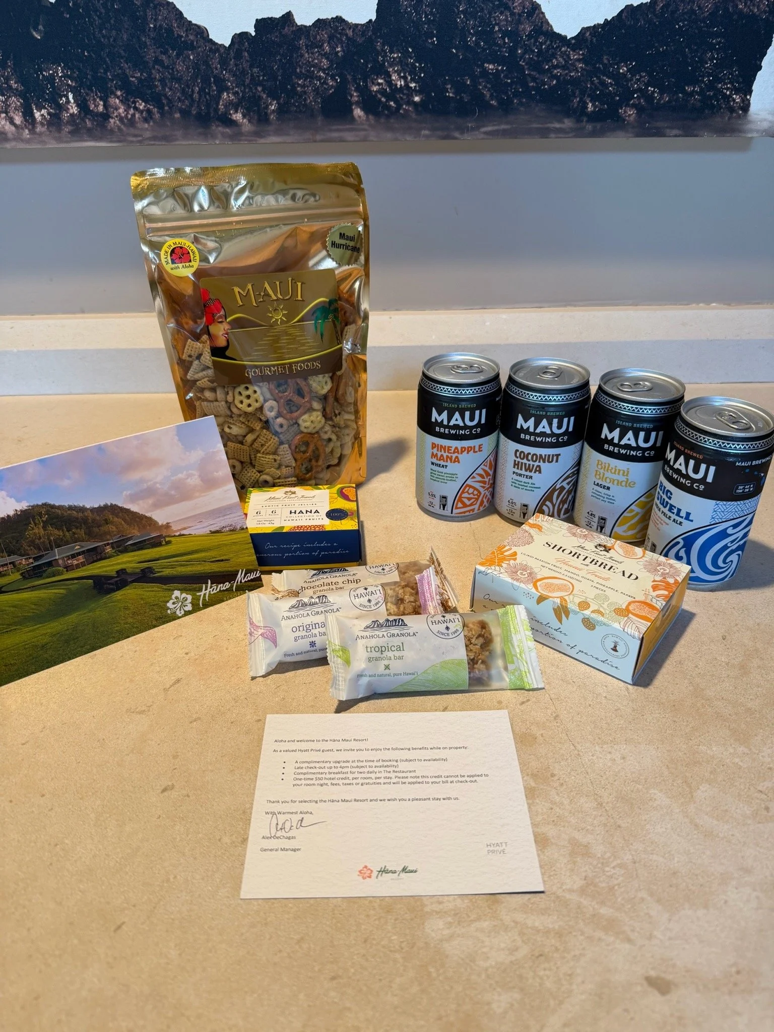 Welcome amenity at Hana-Maui Resort featuring local Maui snacks, Hawaiian shortbread cookies, granola bars, Maui Brewing Company beer, and a personalized guest welcome note.