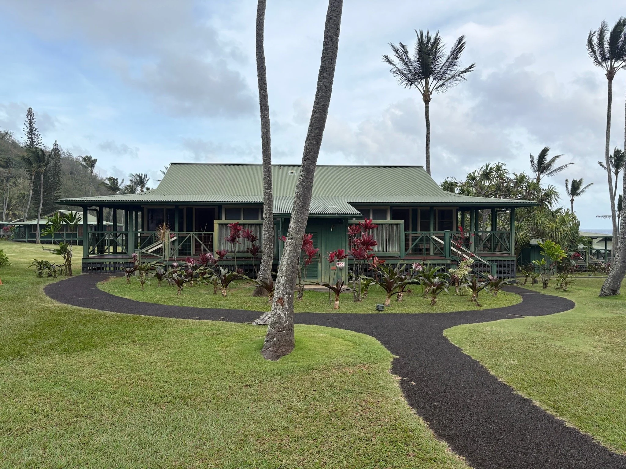 Exterior bungalow at Hana-Maui Resort surrounded by lush lawns, palm trees, and tropical landscaping.