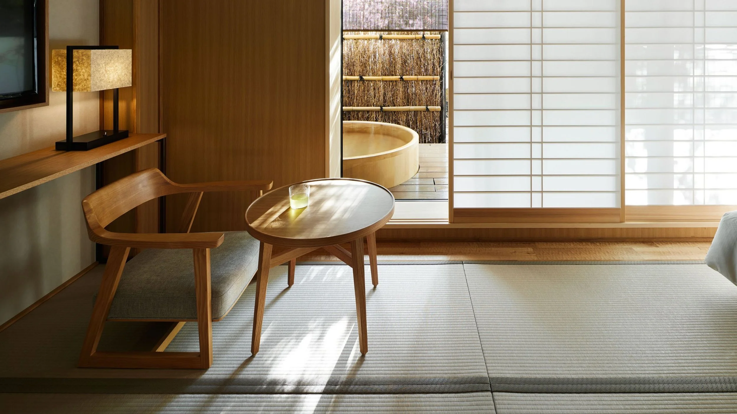 Minimalist Japanese-style room at Yuen Bettei Daita in Tokyo with tatami floors, shoji screens, wooden furnishings, and a private outdoor soaking tub—ideal for a serene wellness escape.