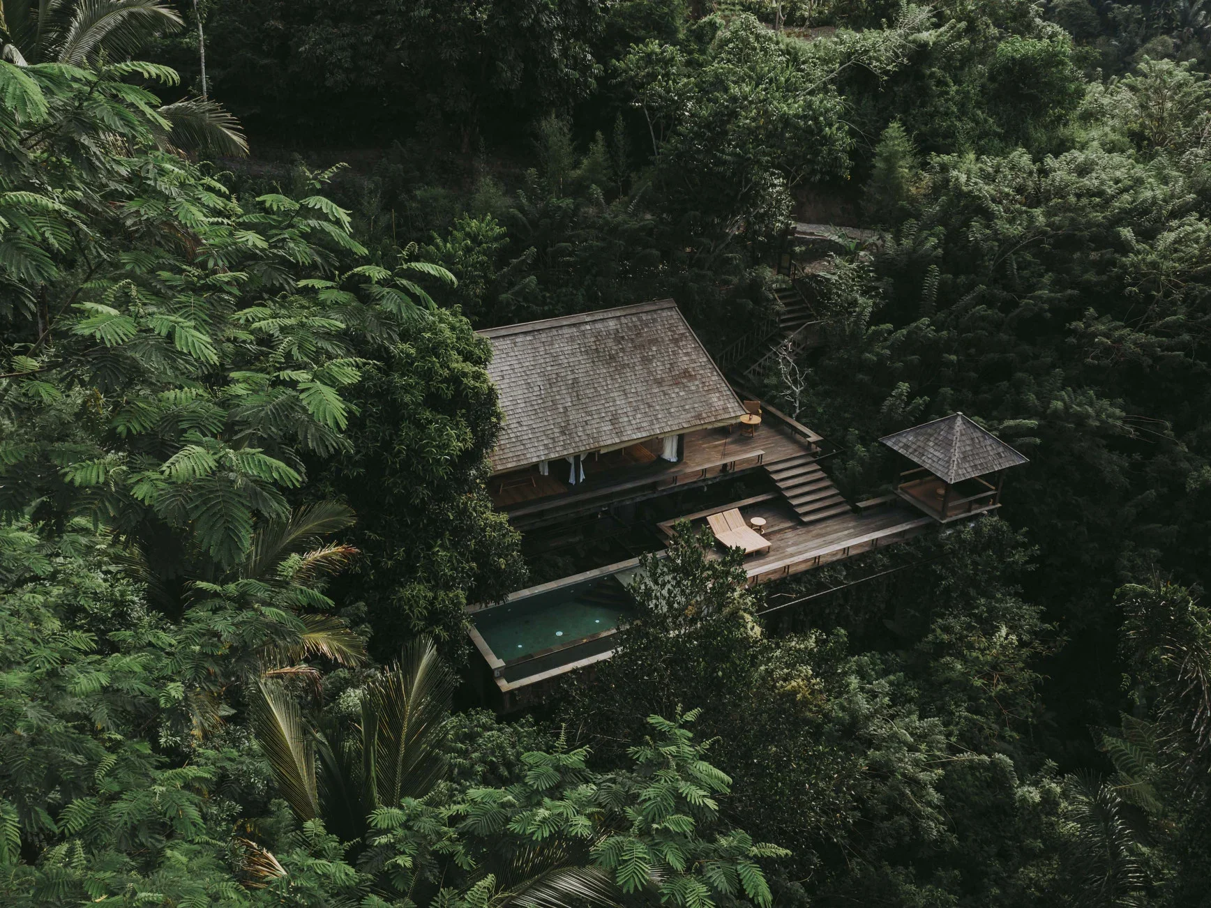 Secluded jungle villa at Buahan, a Banyan Tree Escape in Bali, surrounded by dense tropical rainforest with a private pool and open-air wooden deck—ideal for a peaceful, nature-focused luxury getaway.