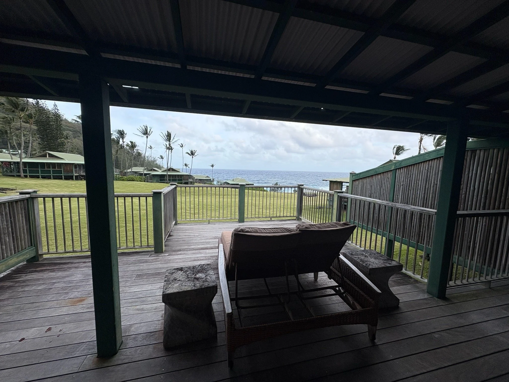 Ocean view from a private balcony at Hana-Maui Resort overlooking lush lawns, palm trees, and the rugged Maui coastline.