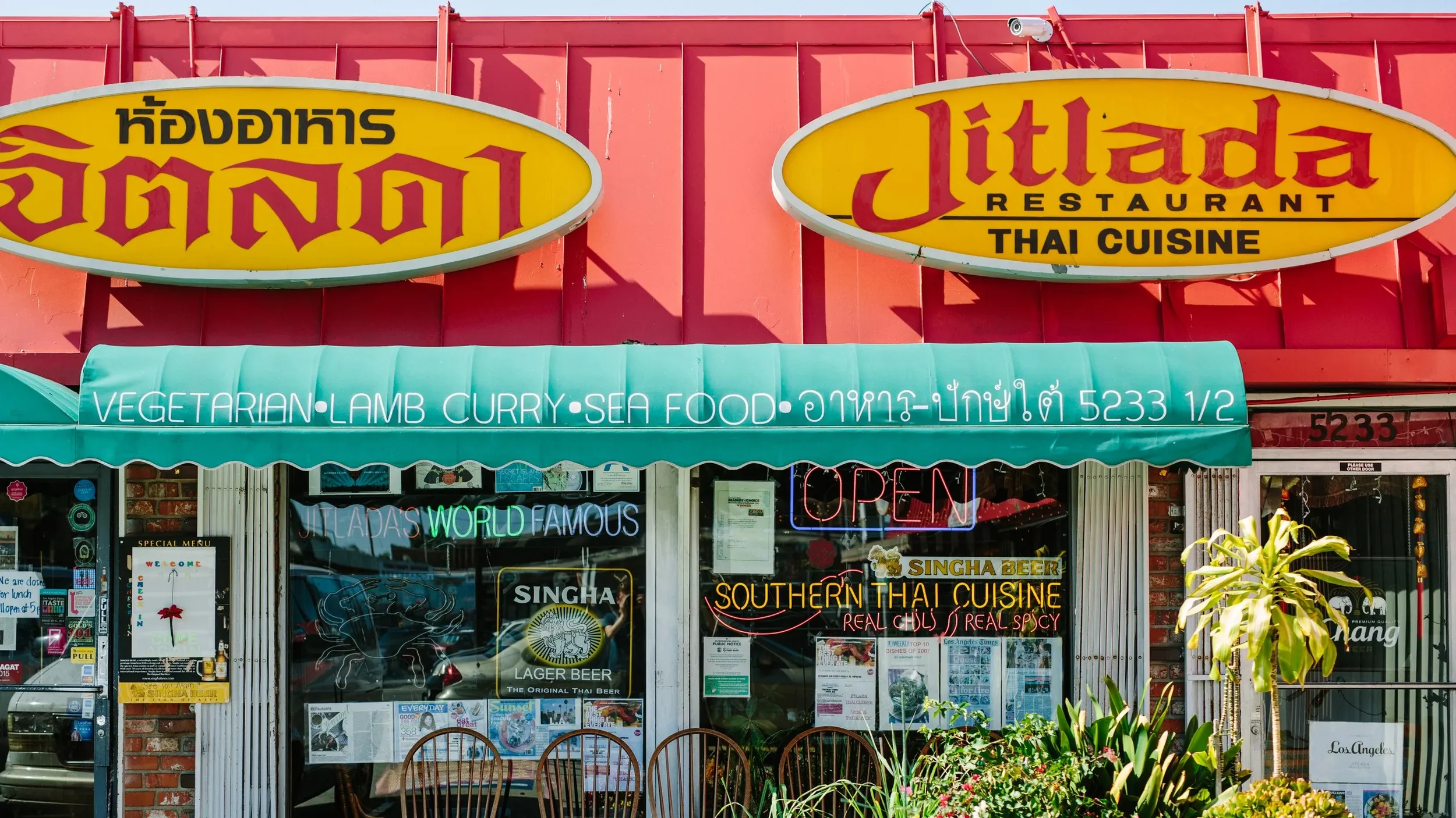 The colorful exterior of Jitlada Restaurant in Los Angeles, a beloved Thai restaurant known for its authentic Southern Thai cuisine, featuring bright yellow signage, neon window displays, and a vibrant neighborhood storefront.