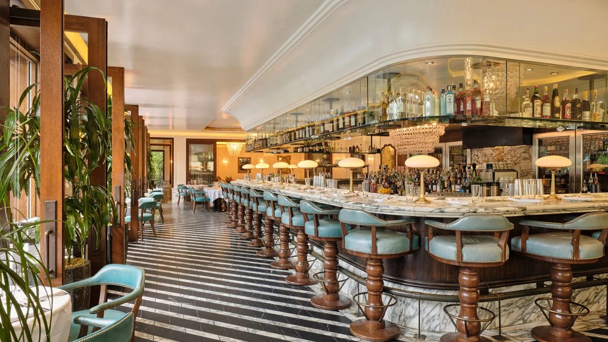An elegant Los Angeles restaurant features a marble bar, plush seating, crystal chandeliers, and warm ambient lighting, creating a sophisticated setting for cocktails, fine dining, and special occasions.