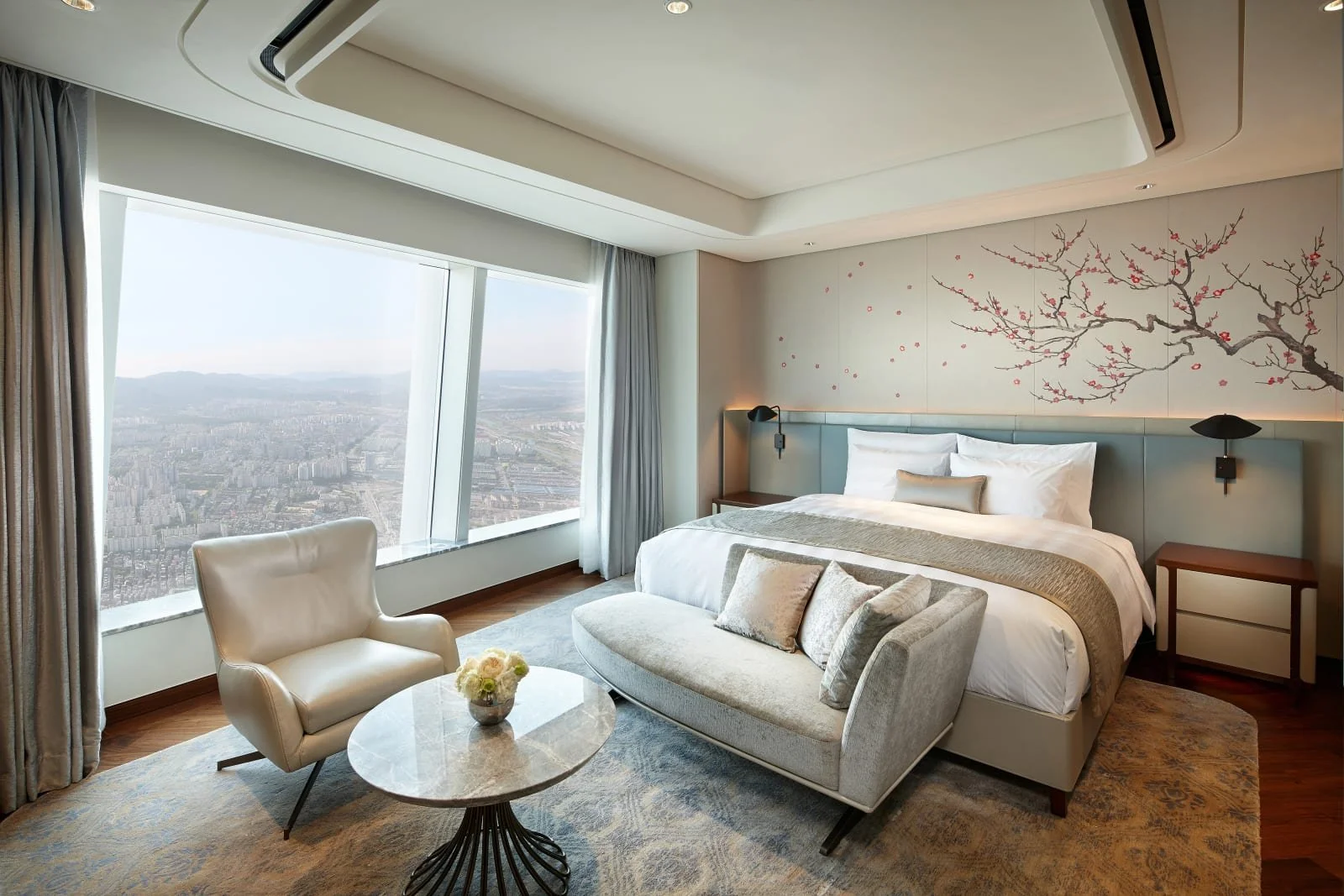 Premier Double room at Signiel Seoul featuring a king bed, modern Korean design, cherry blossom wall art, and panoramic Seoul skyline views.