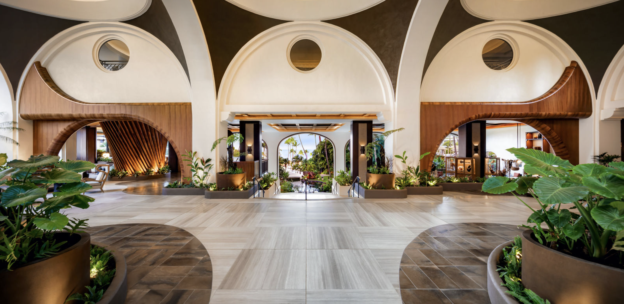 Elegant open-air lobby with arched architecture and lush tropical greenery at Fairmont Kea Lani in Maui
