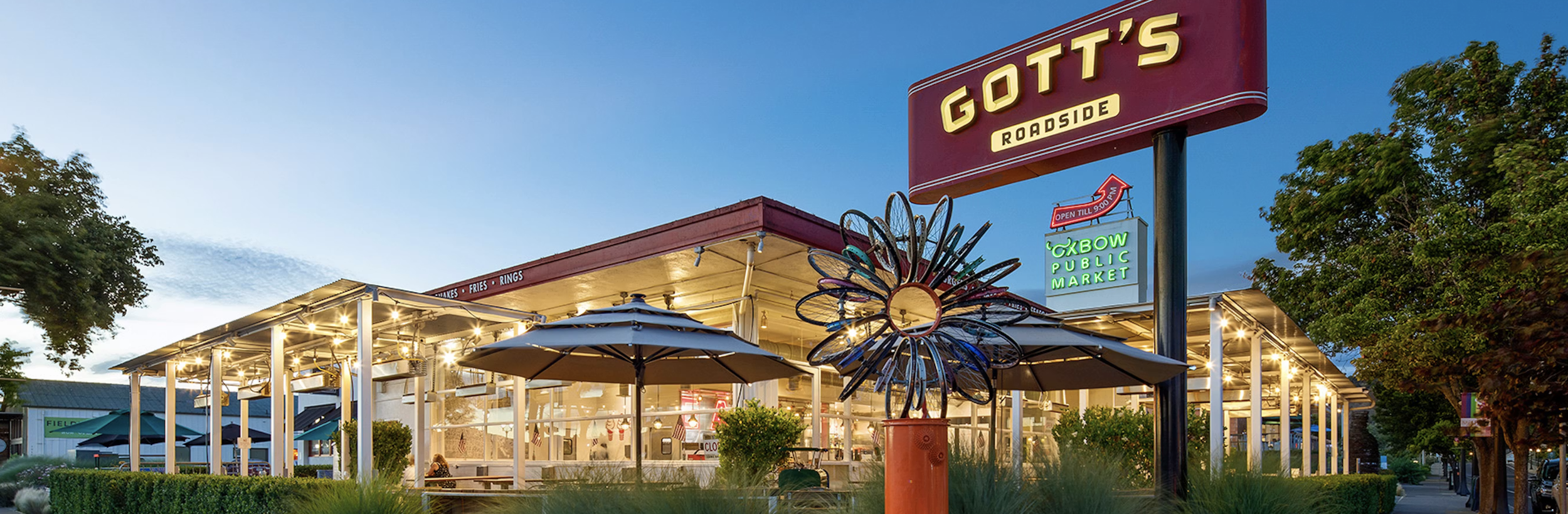 Outdoor wine tasting overlooking Napa Valley vineyards, featuring a bottle of wine, tasting glasses, and scenic vineyard views framed by rolling hills at golden hour.