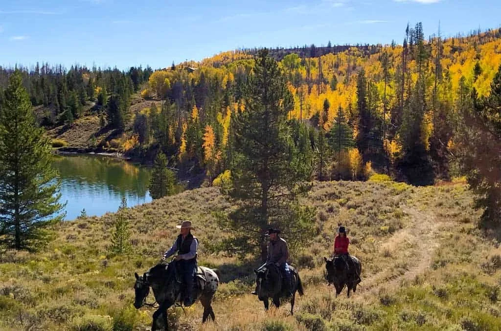 Horseback riding at C Lazy U Ranch through scenic Colorado landscape with river views and colorful fall foliage