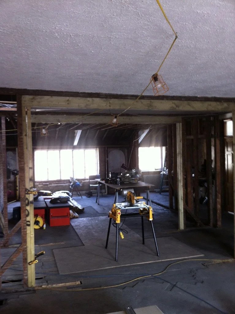 A vintage wooden chair with a curved backrest, upholstered with a white fluffy sheepskin cushion, standing on three wooden legs.