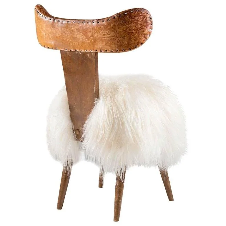A vintage wooden chair with a furry white cushion on the seat.