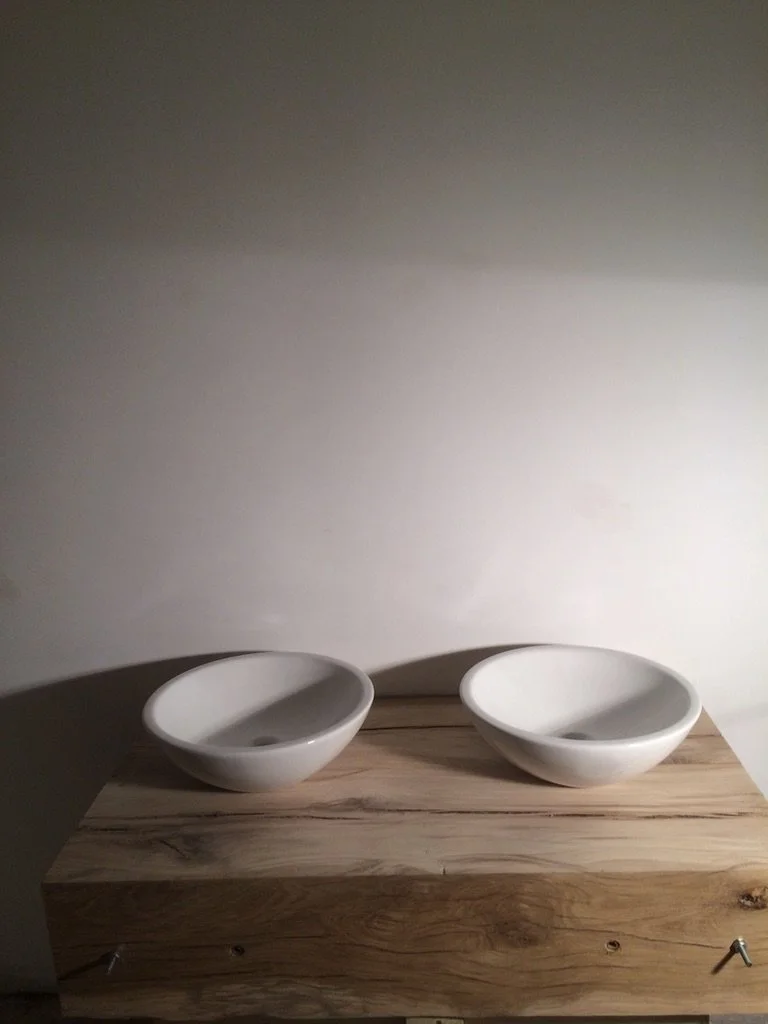 Two white ceramic bowls on a wooden surface against a plain background.