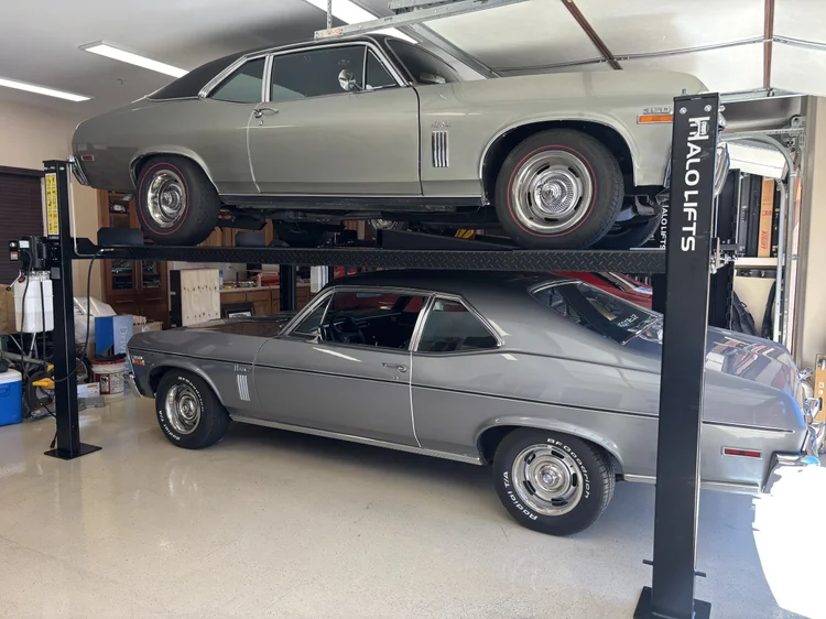 Two classic cars stacked on a four post lift in an Arizona garage