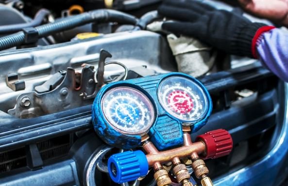 Vintage beige pickup truck parked outside a wooden repair shop with a sign that reads "Motorpool Diesel Repair". Various tools are laid out in front of the truck, and the scene is illuminated by natural daylight.