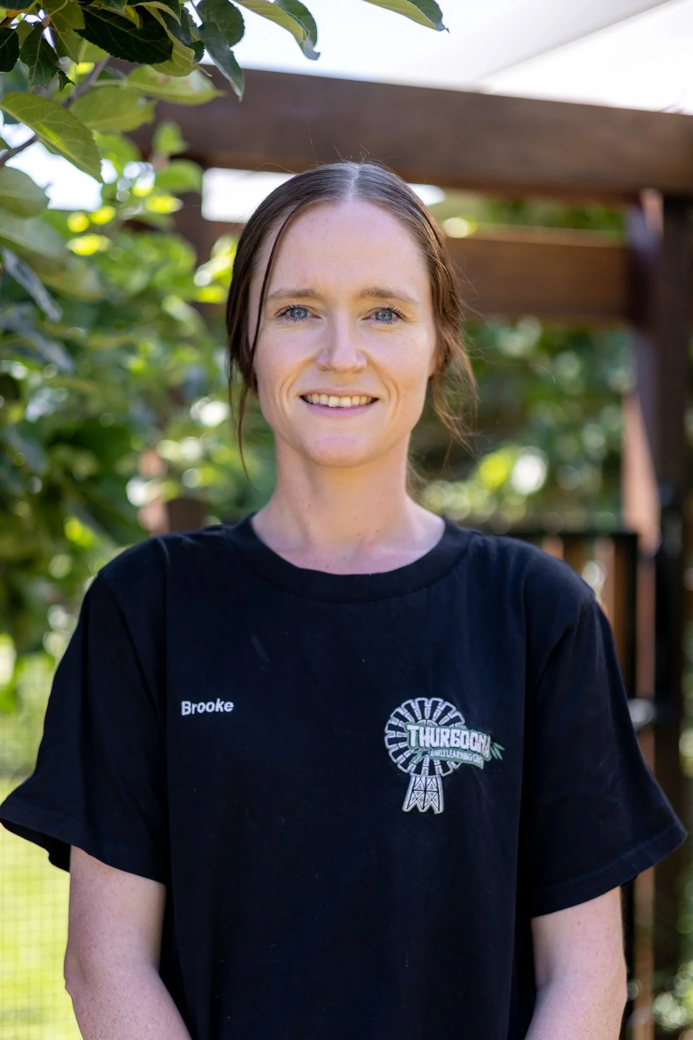 A smiling woman who is a childcare educator, she has the nametag Tanya