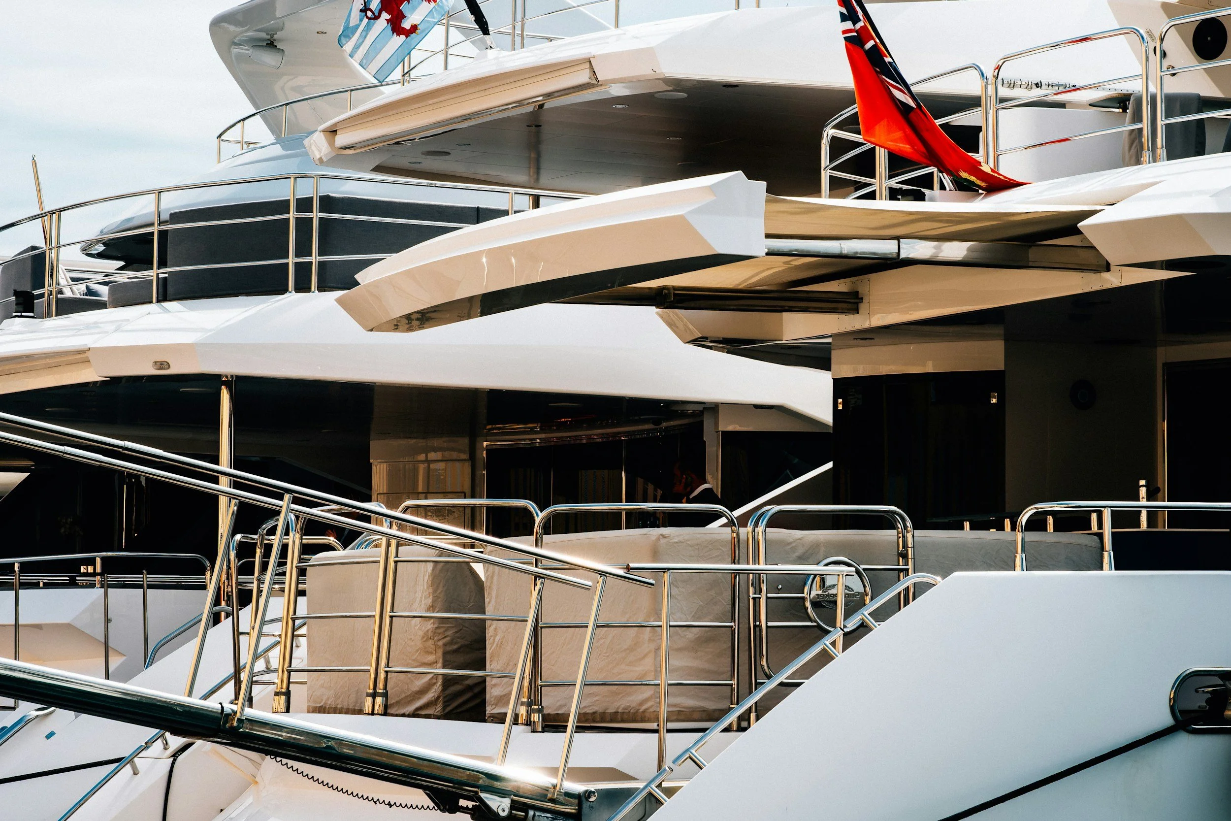 Close-up of a luxury yacht with multiple decks, metal railings, and covered seating areas, docked at a marina.