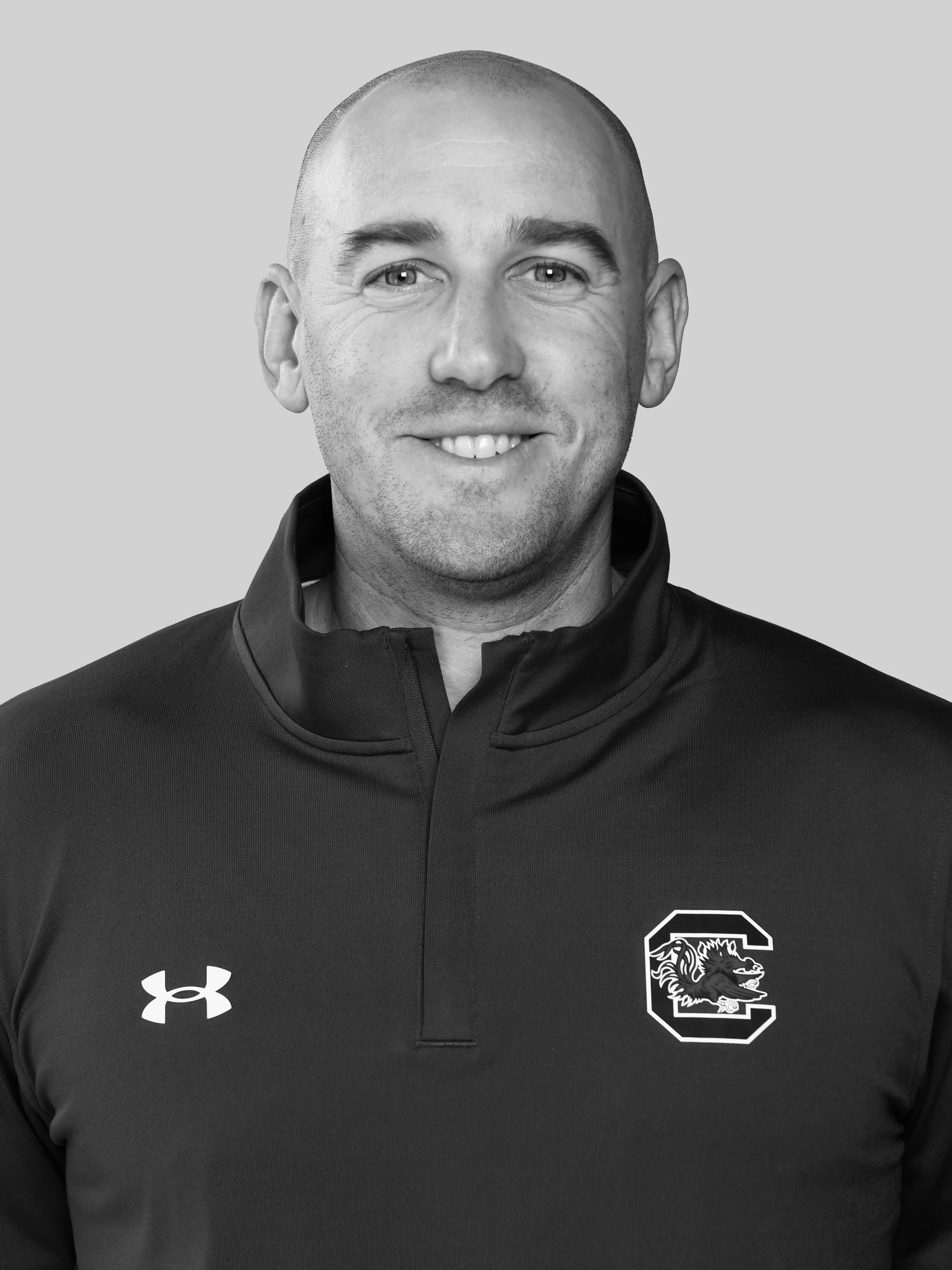 A man in a black sports jacket with an Under Armour logo on the chest and a South Carolina Gamecocks logo on the right side.