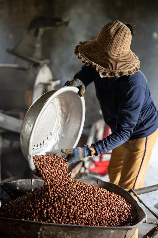 a woman is roasting peanuts in a factory in central Vietnam