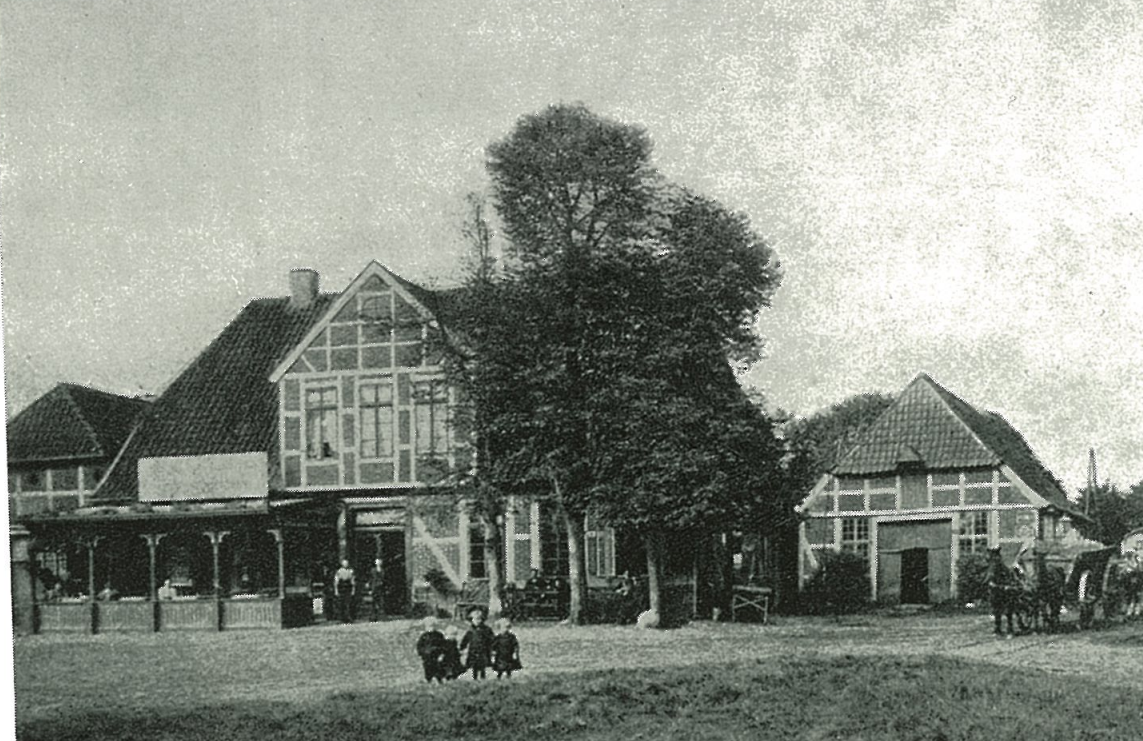 Black and white photograph of a large house with a tall tree in front, and a smaller building to the right. Several people, children and adults, are in front of the buildings. Horse-drawn carriages are also visible.