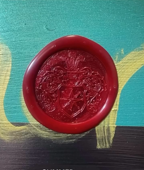 Close-up of a red wax seal with a crest and intricate detailing, resting on a colorful painted surface with blue, yellow, and black sections.