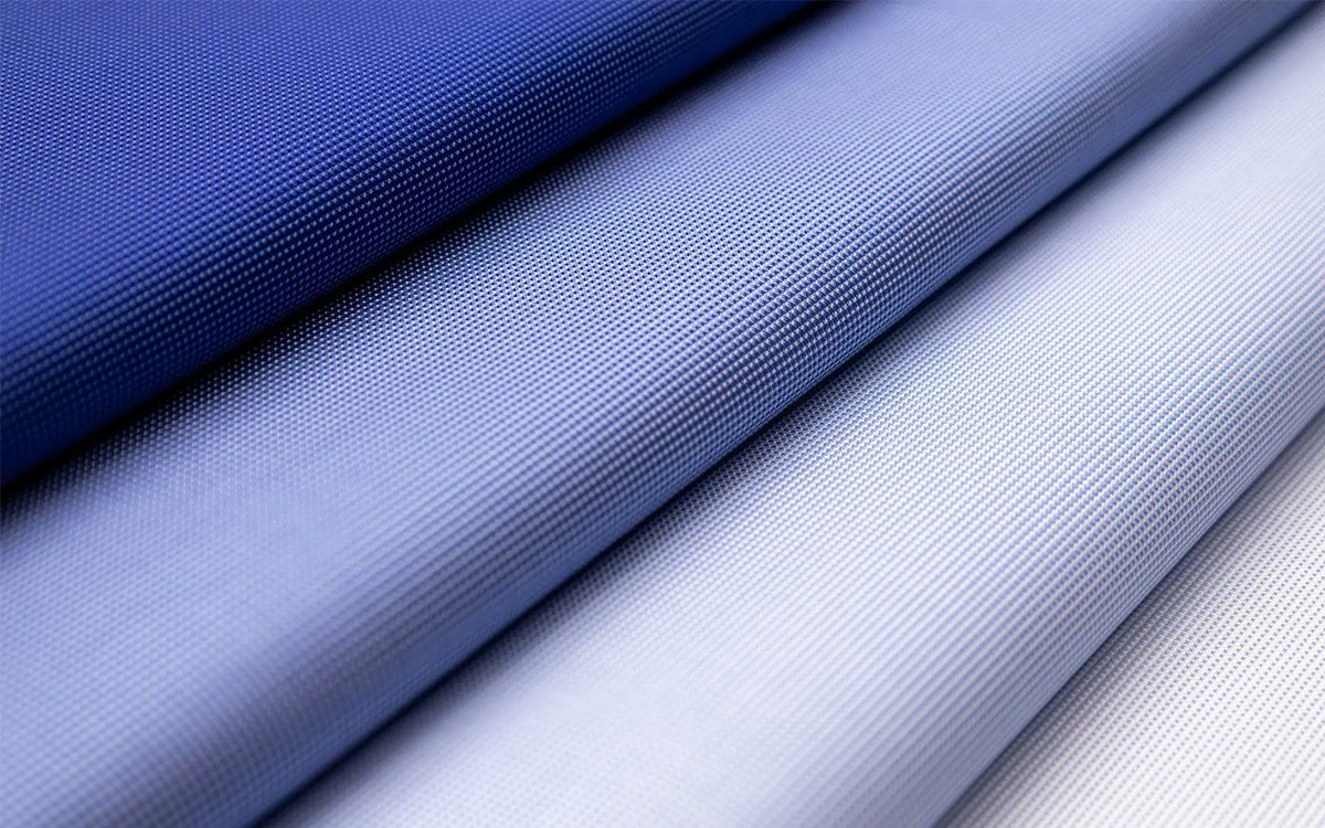 Close-up of four rolls of textured fabric or material in shades of blue and light gray.
