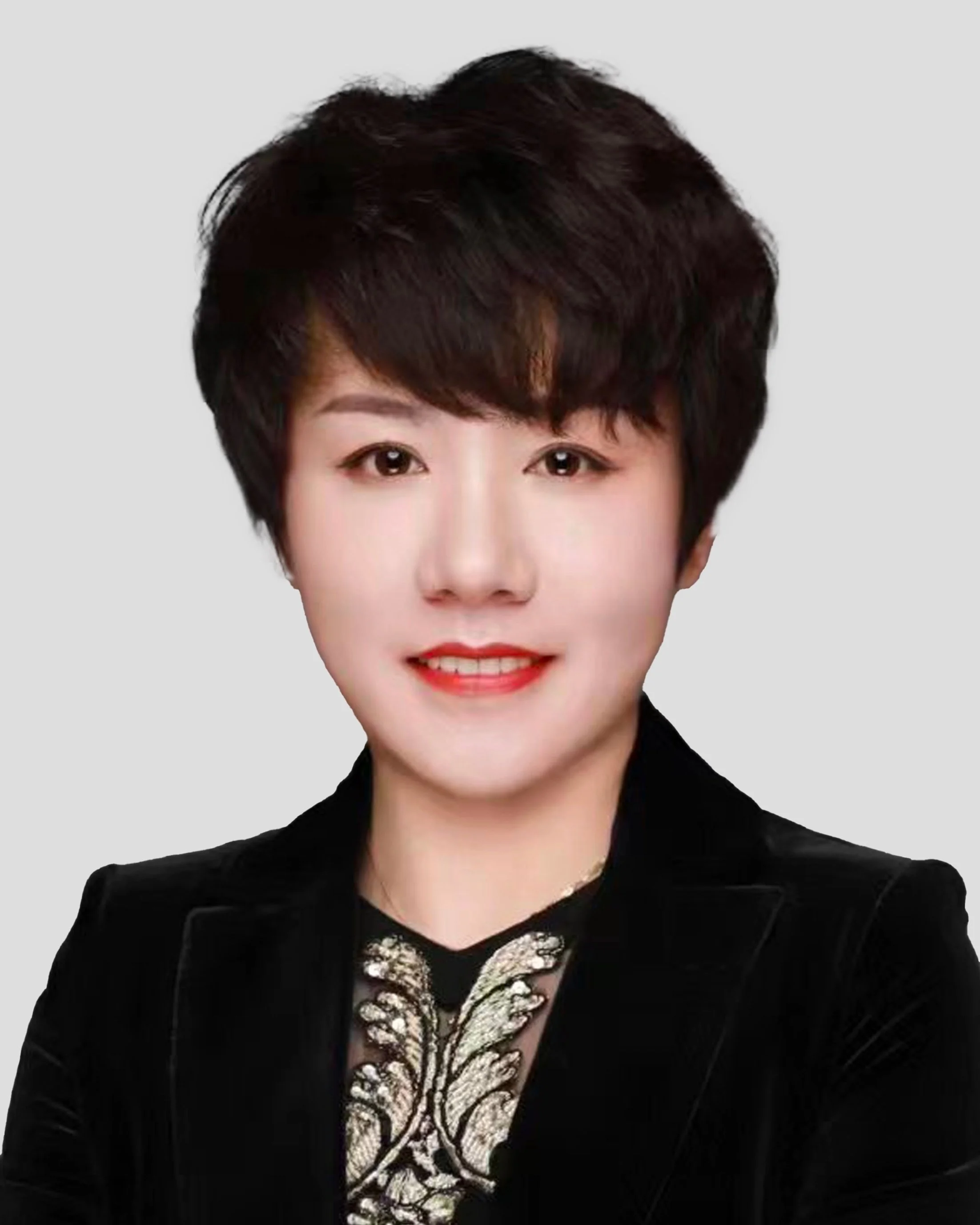 Portrait of a woman with short dark hair, wearing a black jacket and a decorative top with embroidery.