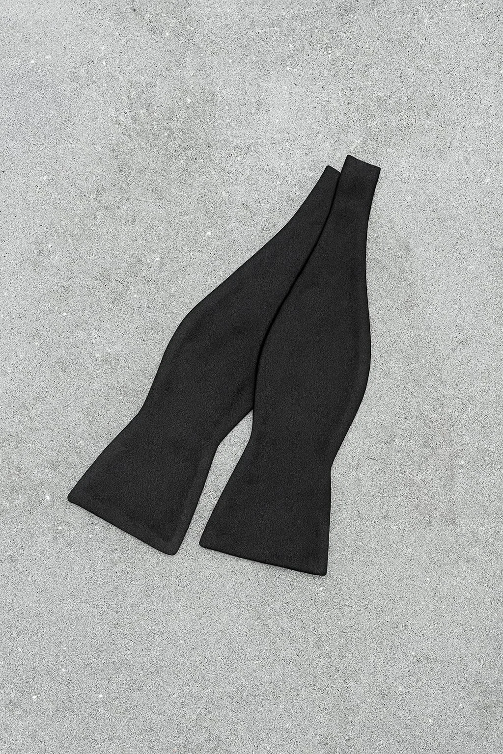 Pair of black high-heeled shoes on gray surface.