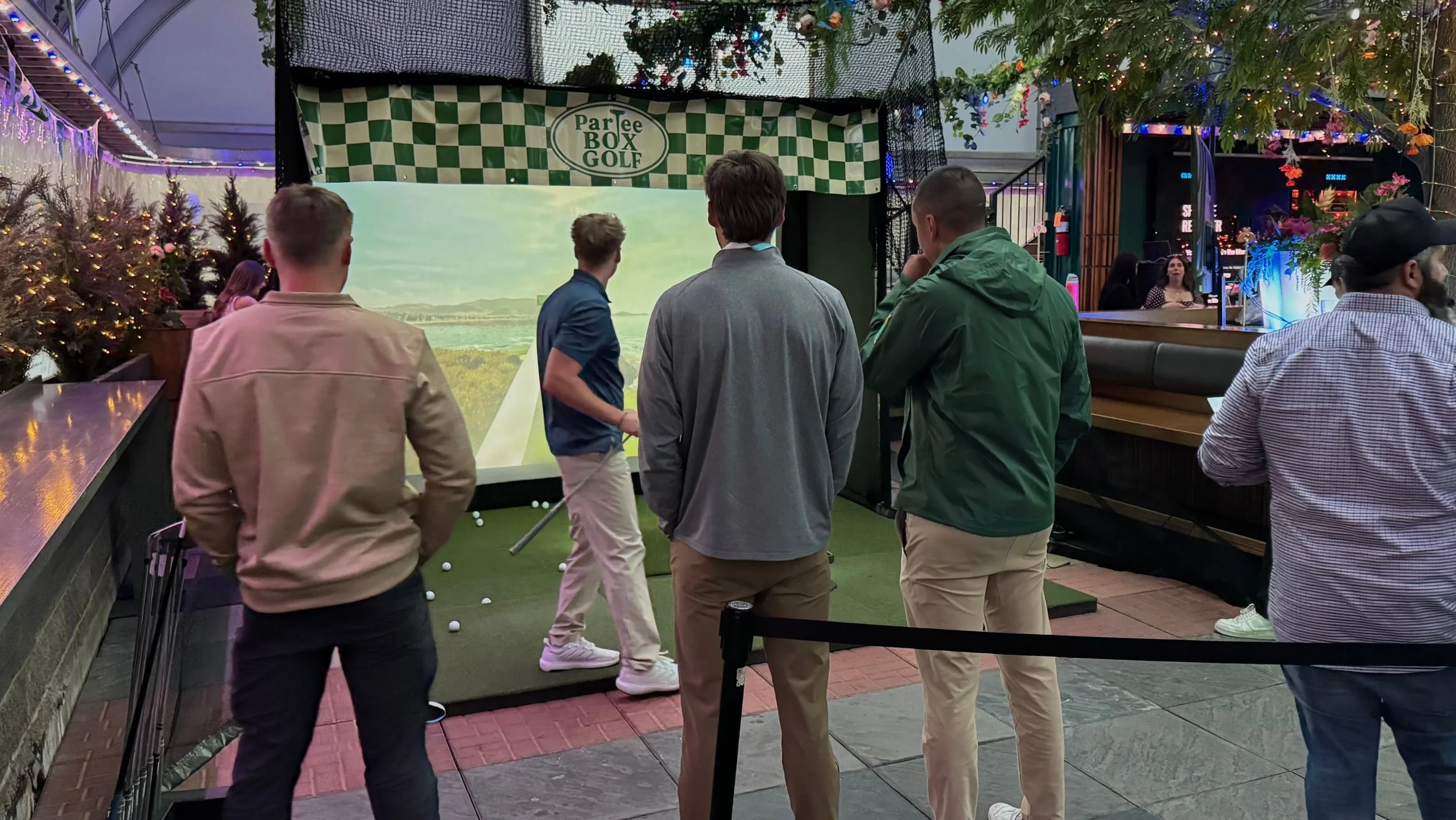 Guests gathering around the ParTee Box Golf mobile golf simulator during a Calgary event