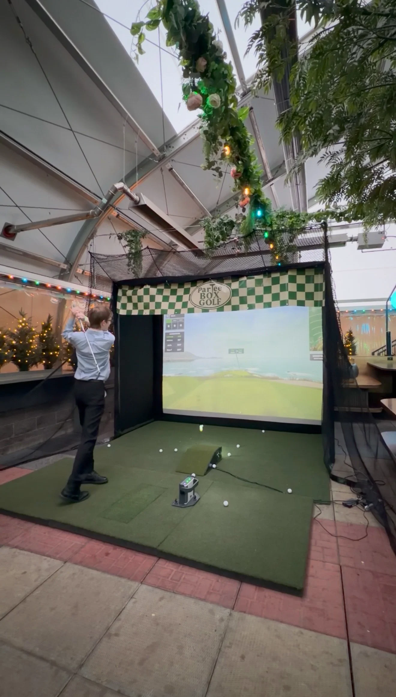 Guest taking a swing on the ParTee Box Golf mobile simulator during an event