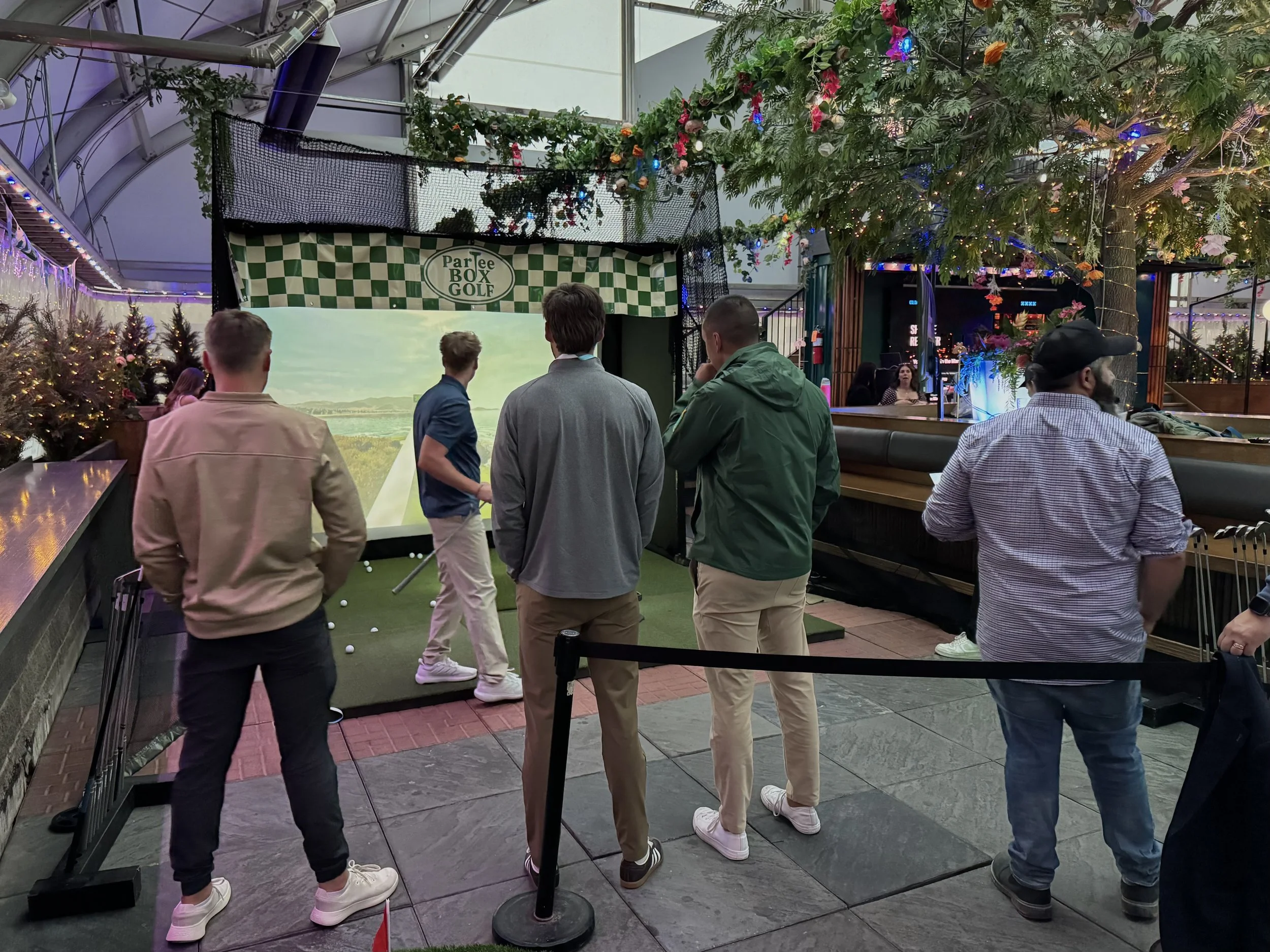 Guests watching a golf simulator competition at a ParTee Box Golf event in Calgary