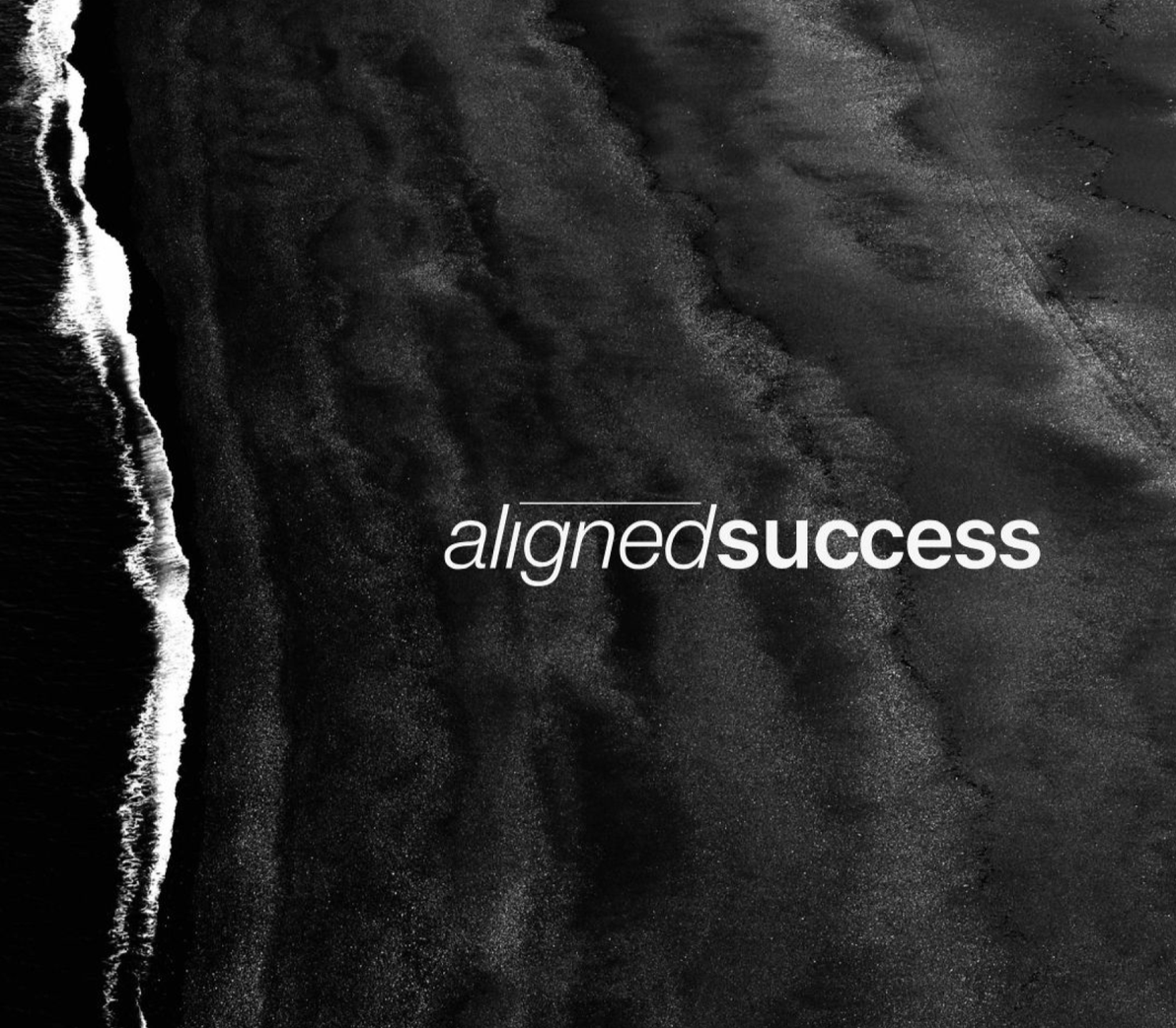 Black and white aerial view of a sandy beach with waves crashing on the shore, with the words "aligned success" overlayed.