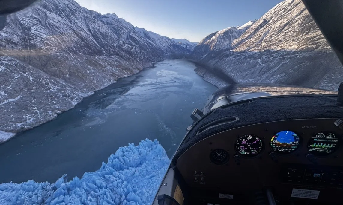 Cessna 180, Bush plane, flying over a glacier near mountains.