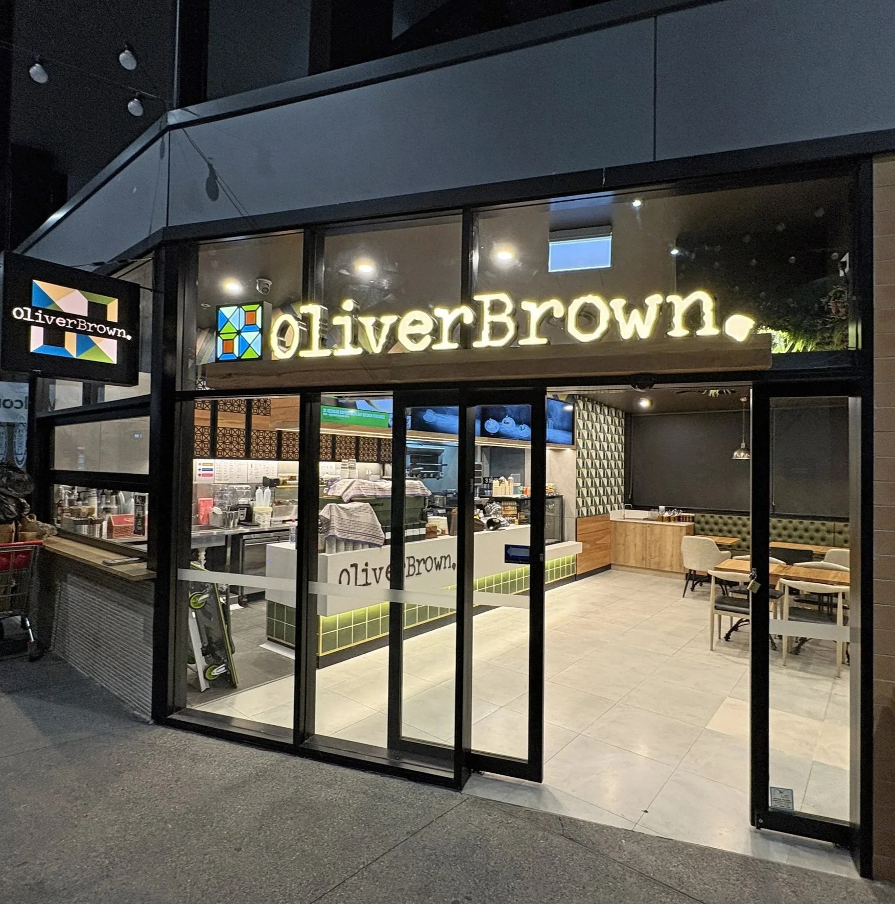 Completed Oliver Brown Lake Macquarie café fit-out showcasing the fully glazed shopfront, illuminated signage and dedicated takeaway service window.