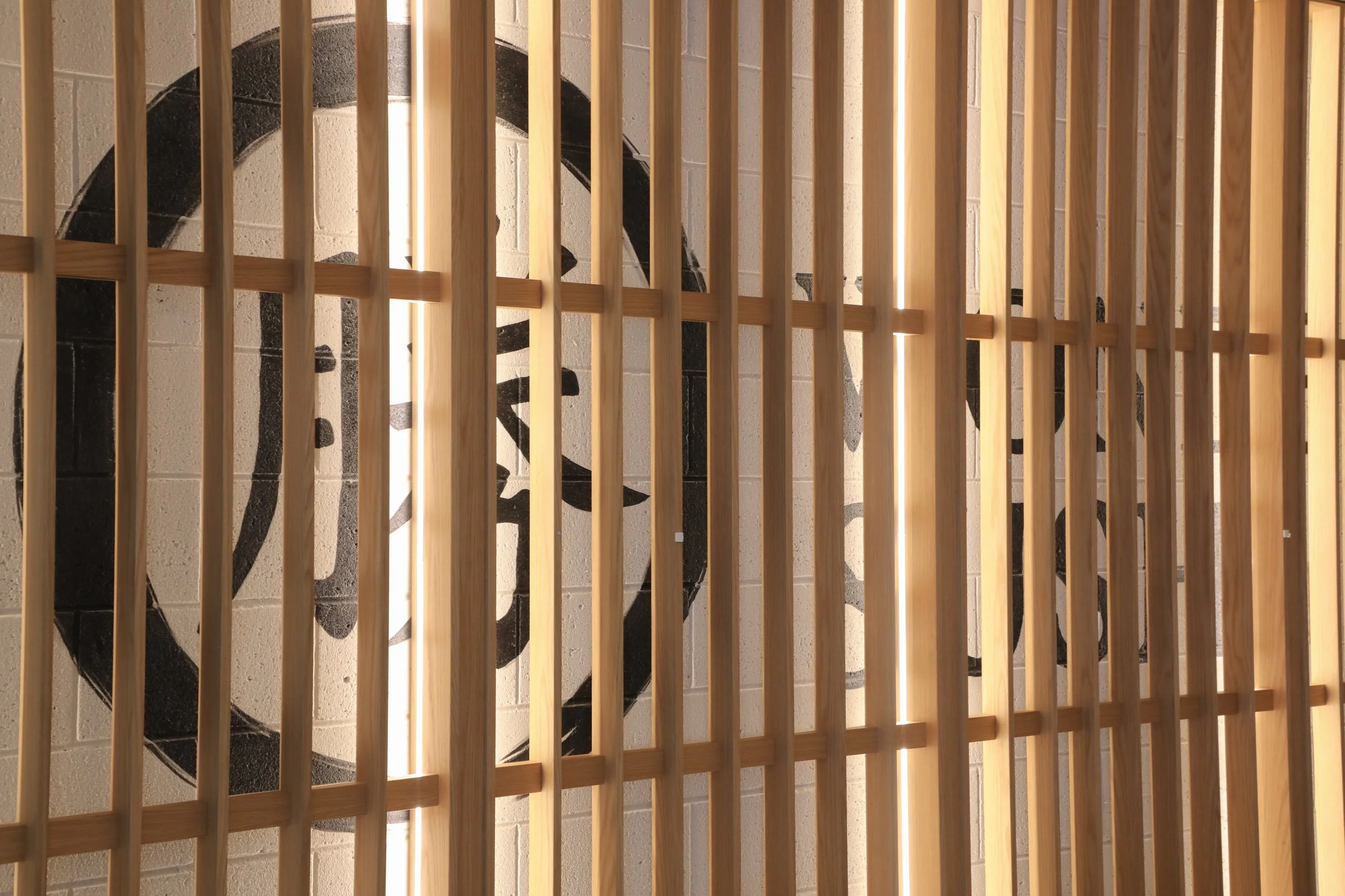 Bespoke timber batten installation illuminated by integrated LED lighting to emphasise natural materiality.