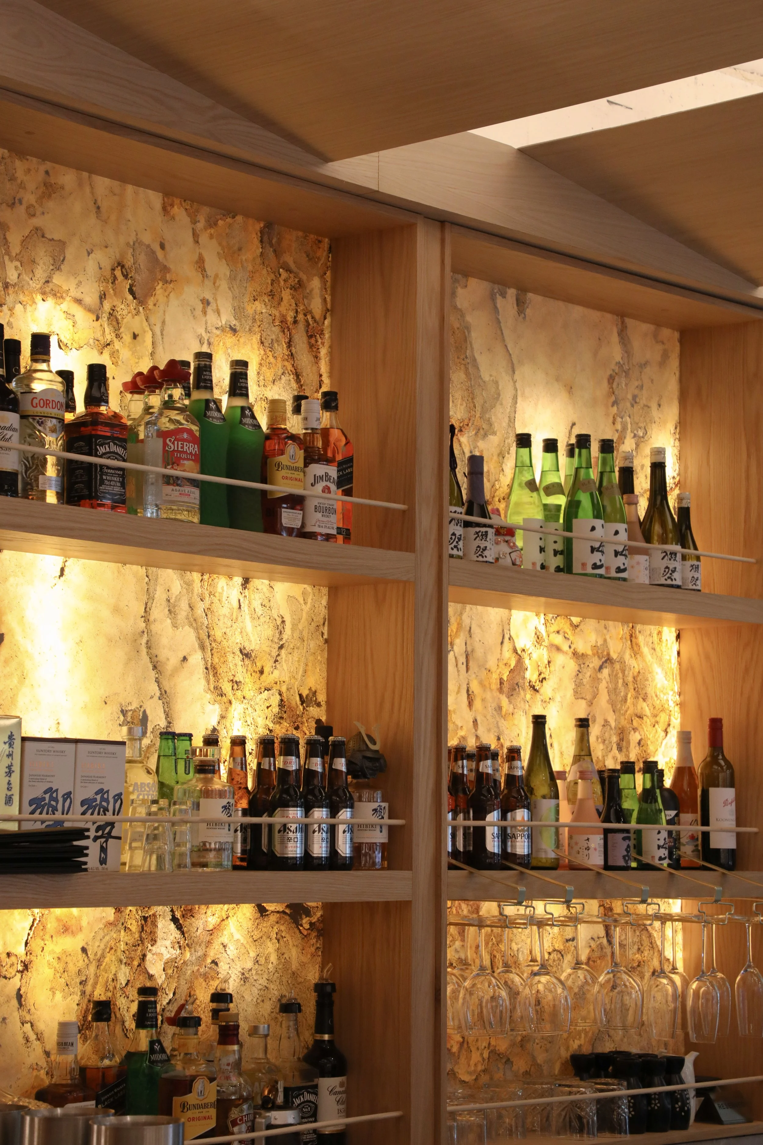 Completed hospitality fit-out for Wonder Sushi Norwest, showcasing a backlit custom stone wall with integrated beverage display.