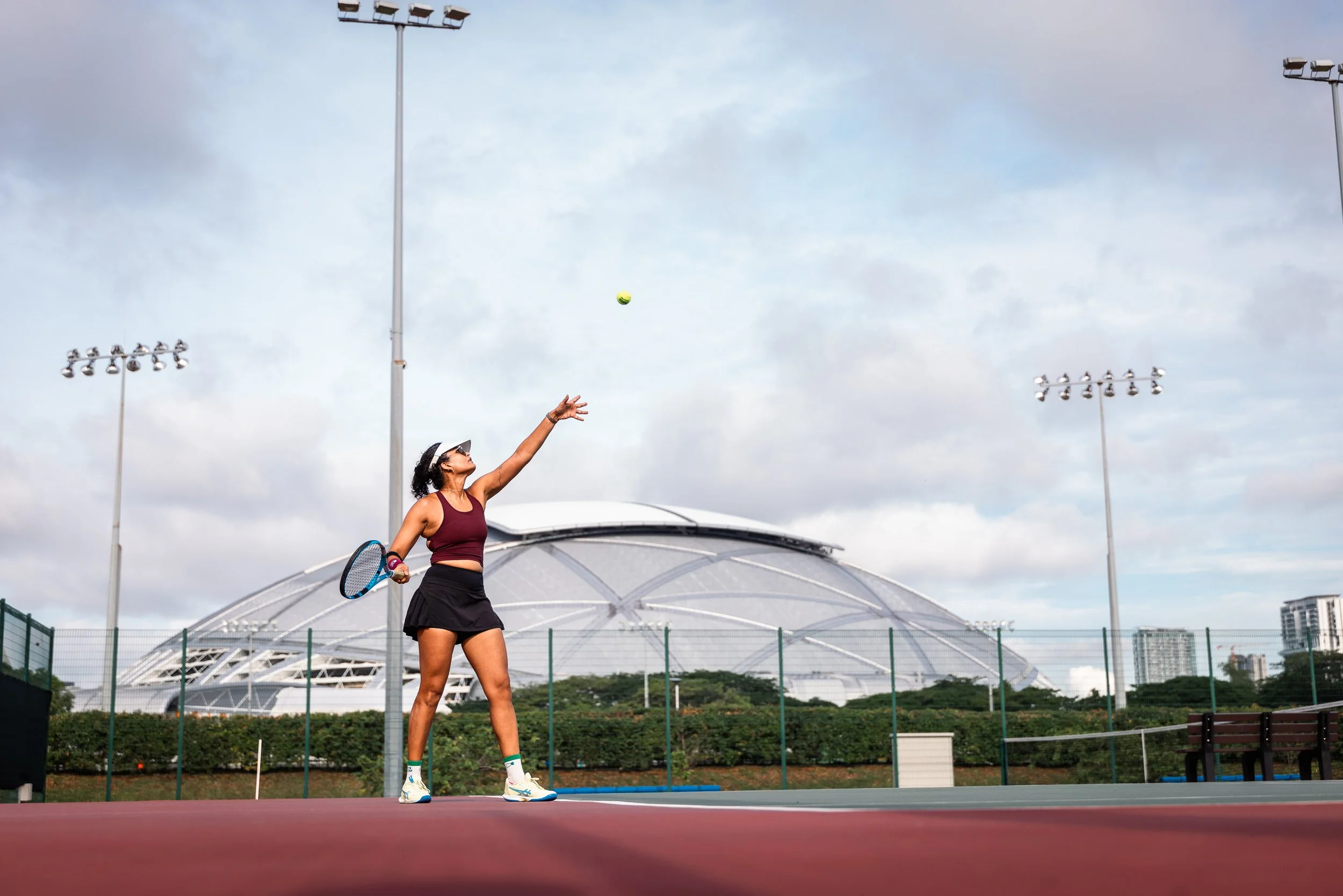 WITS player serving at Kallang Tennis Centre, Singapore Sports Hub in background