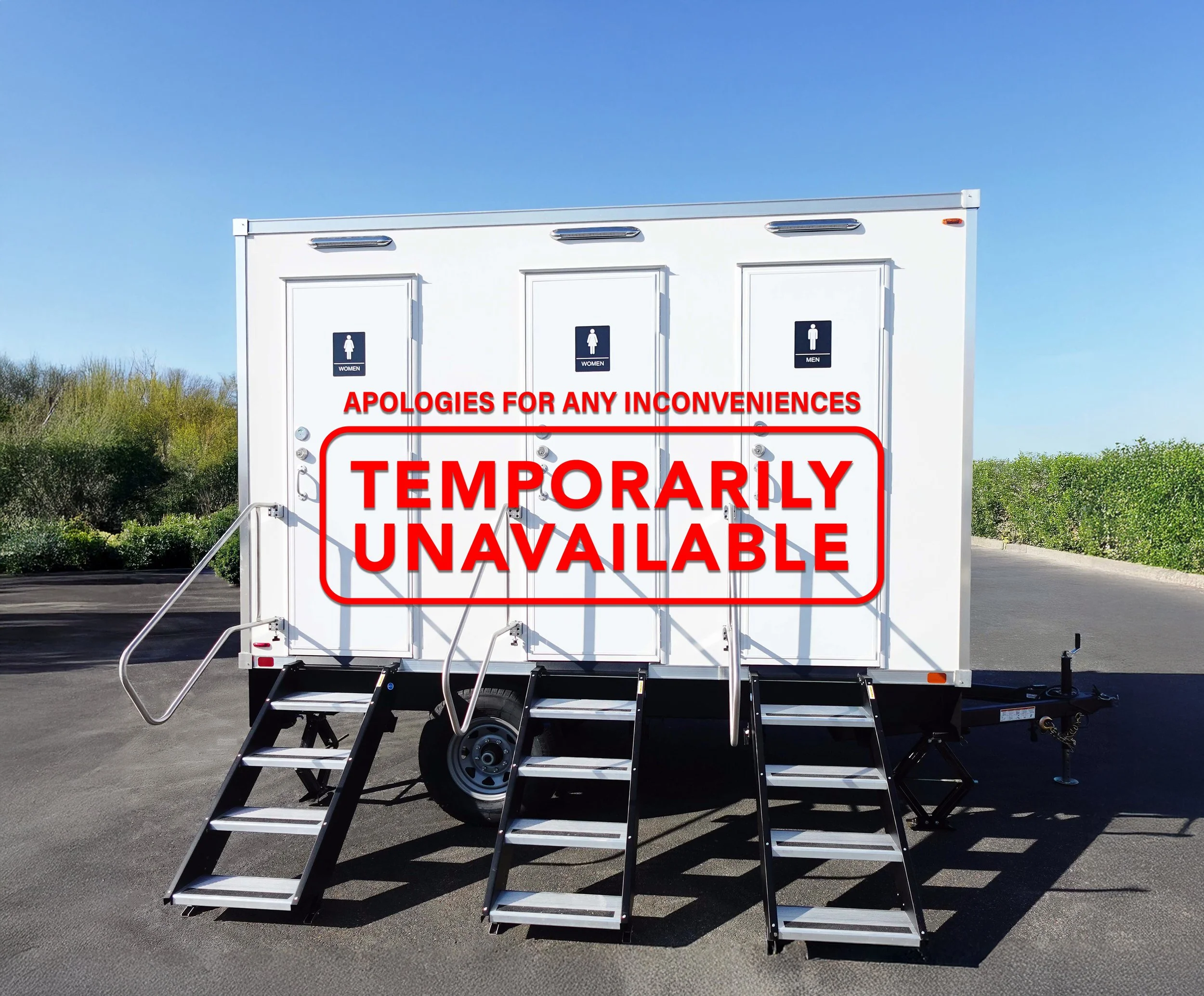 Portable restroom trailer with three doors, labeled for women, women, and men, on a paved surface outdoors with greenery in the background.