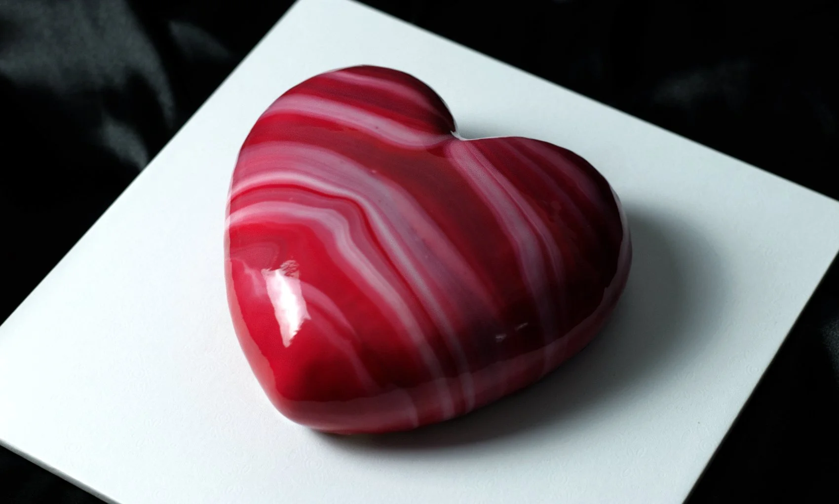 Luxury round entremet dessert by AFTERSIX with blue marble mirror glaze, presented on a white base against a dark background, tagged with the name 'AMORA'.