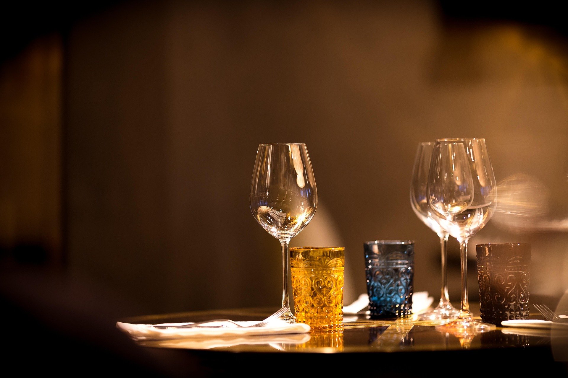 Empty wine glasses and colorful drinking glasses on a table with a blurred background.
