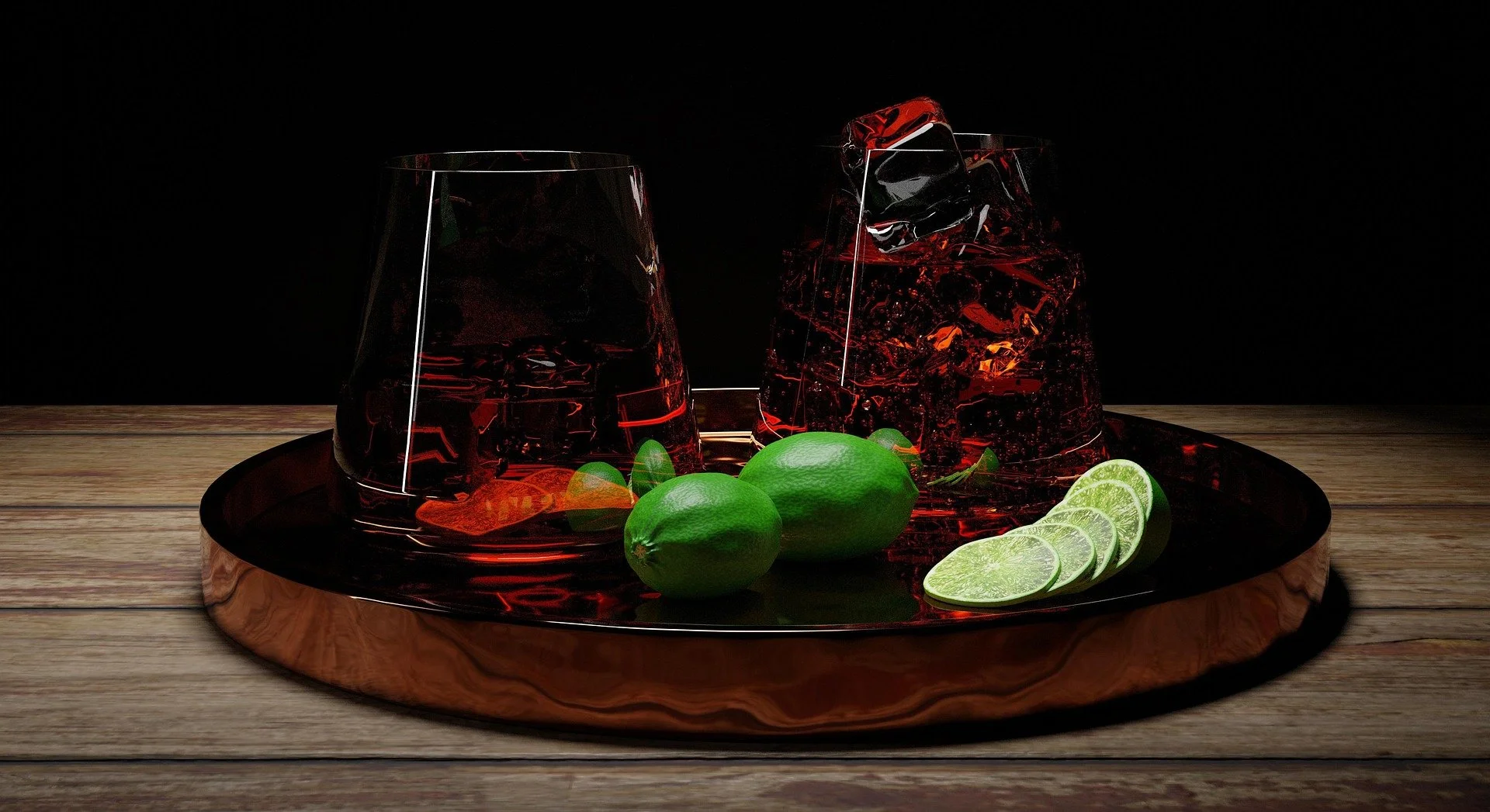 Two glasses of red drink with ice, two whole limes and lime slices on a black tray on a wooden surface against a dark background.