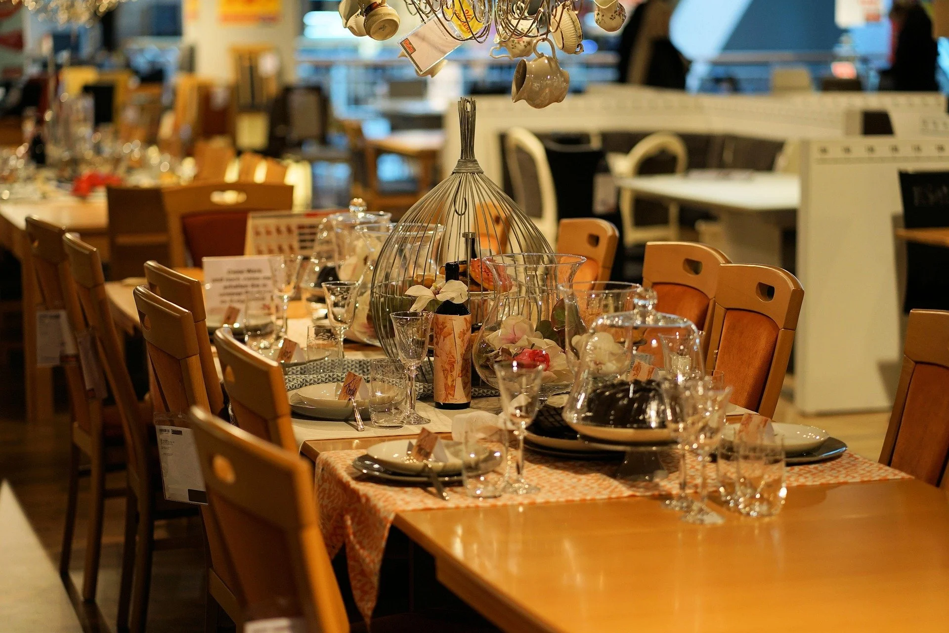 A dining table set for a meal with plates, glasses, and cutlery, decorated with vases and ornaments, in a restaurant or event space with warm lighting.