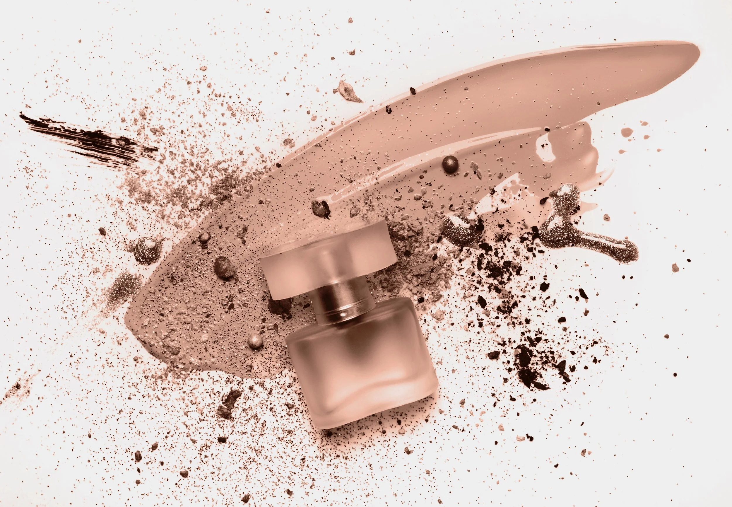 A perfume bottle, eyeshadow, and makeup smeared with blush powder on a white surface.