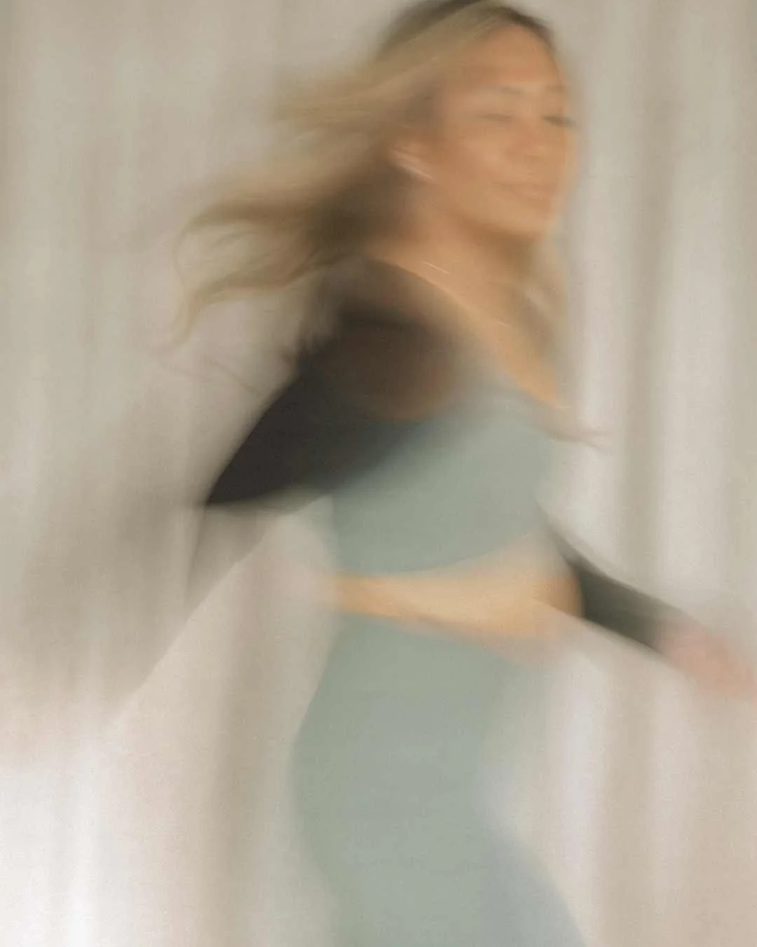 A woman with long hair is captured in motion, creating a blurred, artistic effect.