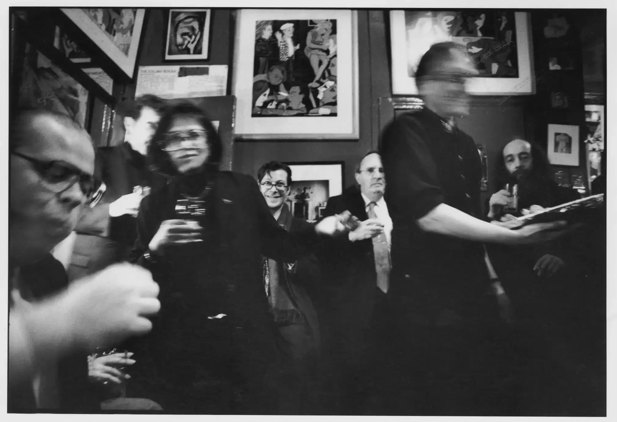 People gathered in a room, enjoying drinks, with artwork on the walls.