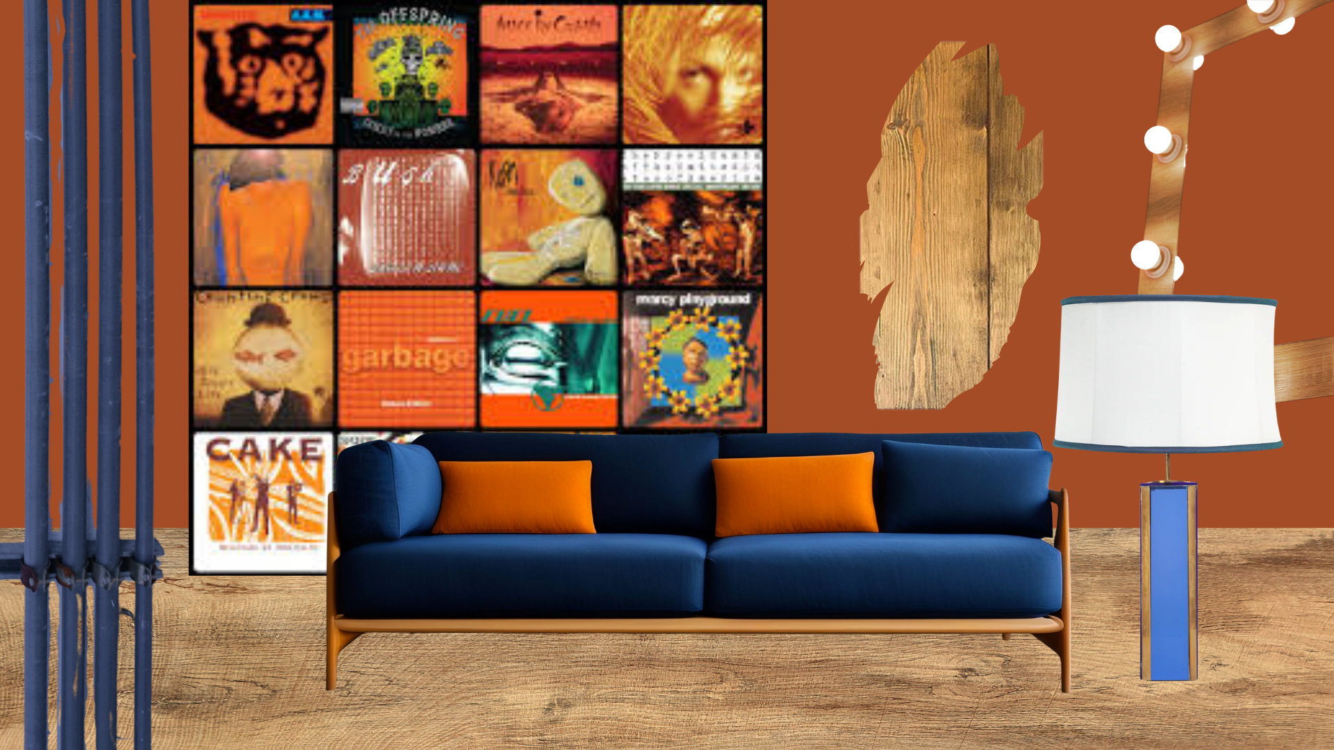 A modern living room with a navy blue sofa with orange pillows, a wooden floor, and a brown wall with vintage album covers. There is a wooden wall art piece, a white and blue lamp, and blue vertical pipes on the left.