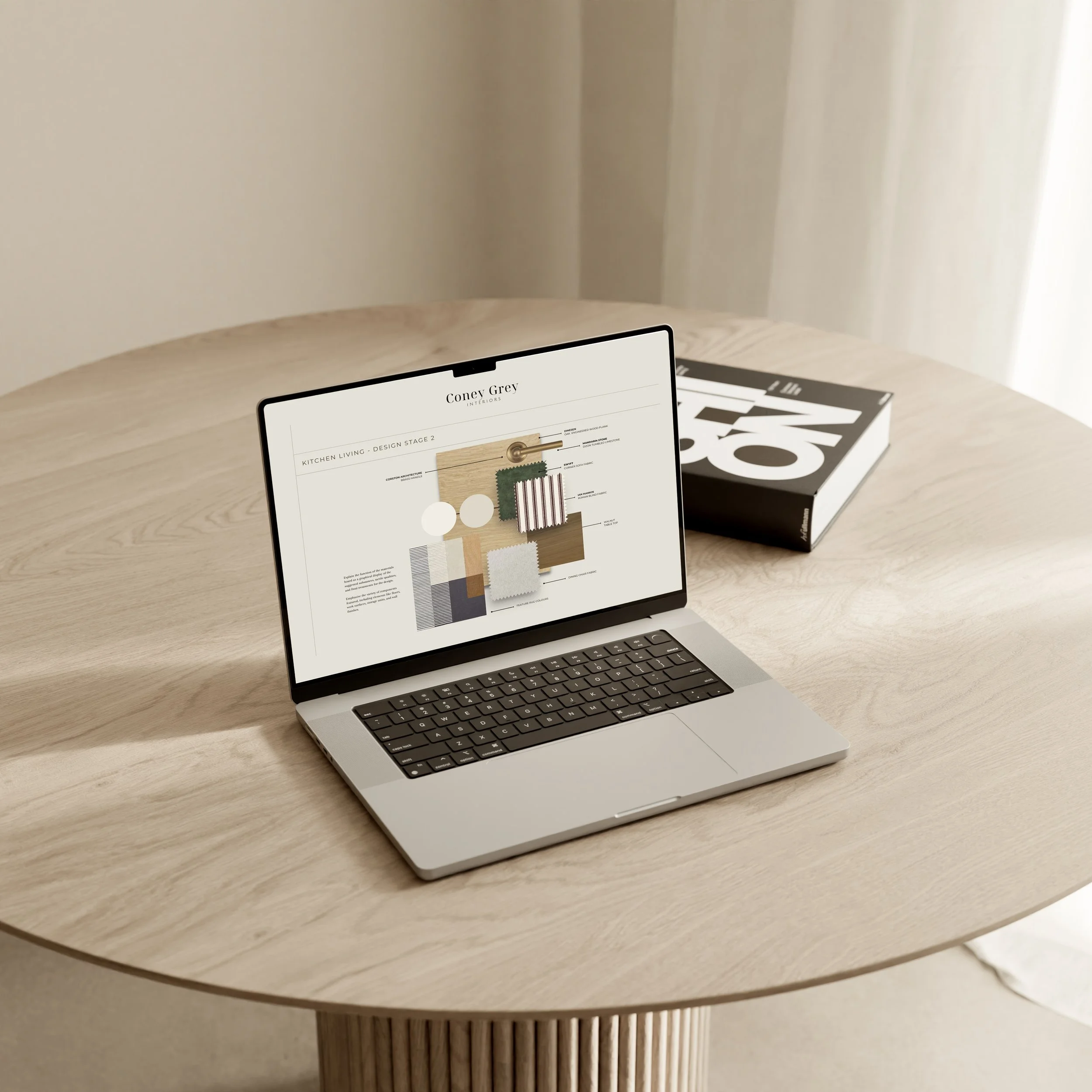 A laptop on a wooden table displaying interior design material samples and moodpboard with a book behind it.